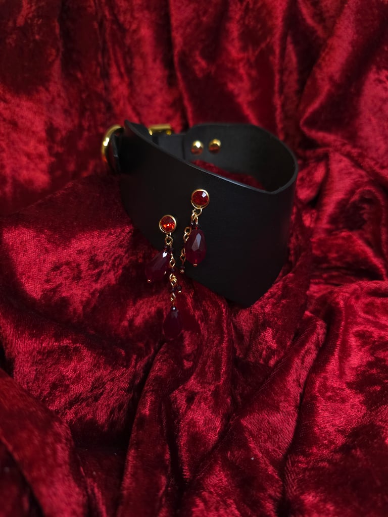 Black leather collar with red beads on a red textured background