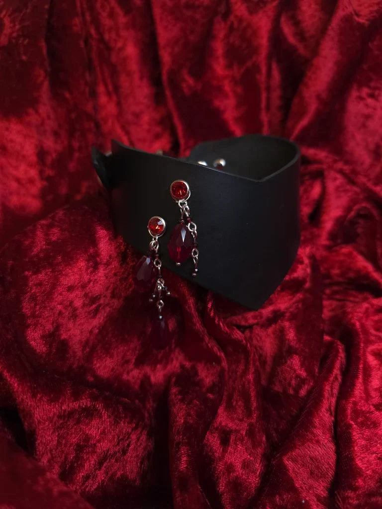 Black leather collar with red embellishments on a red textured background