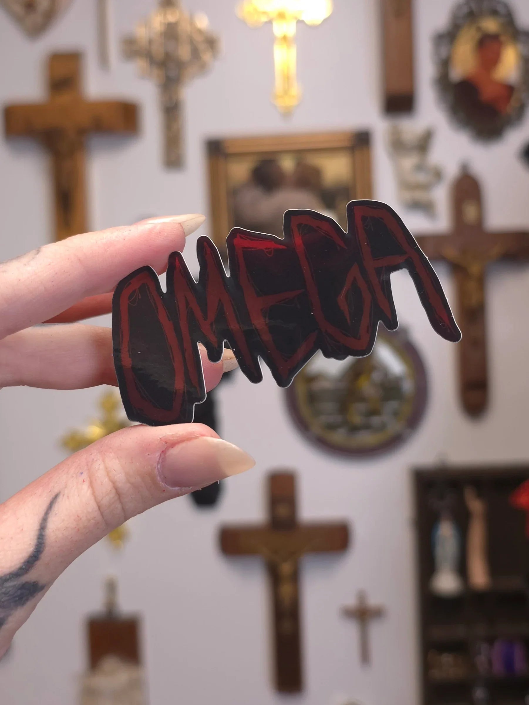 Hand holding a 'OMEGA' sign in front of religious decor