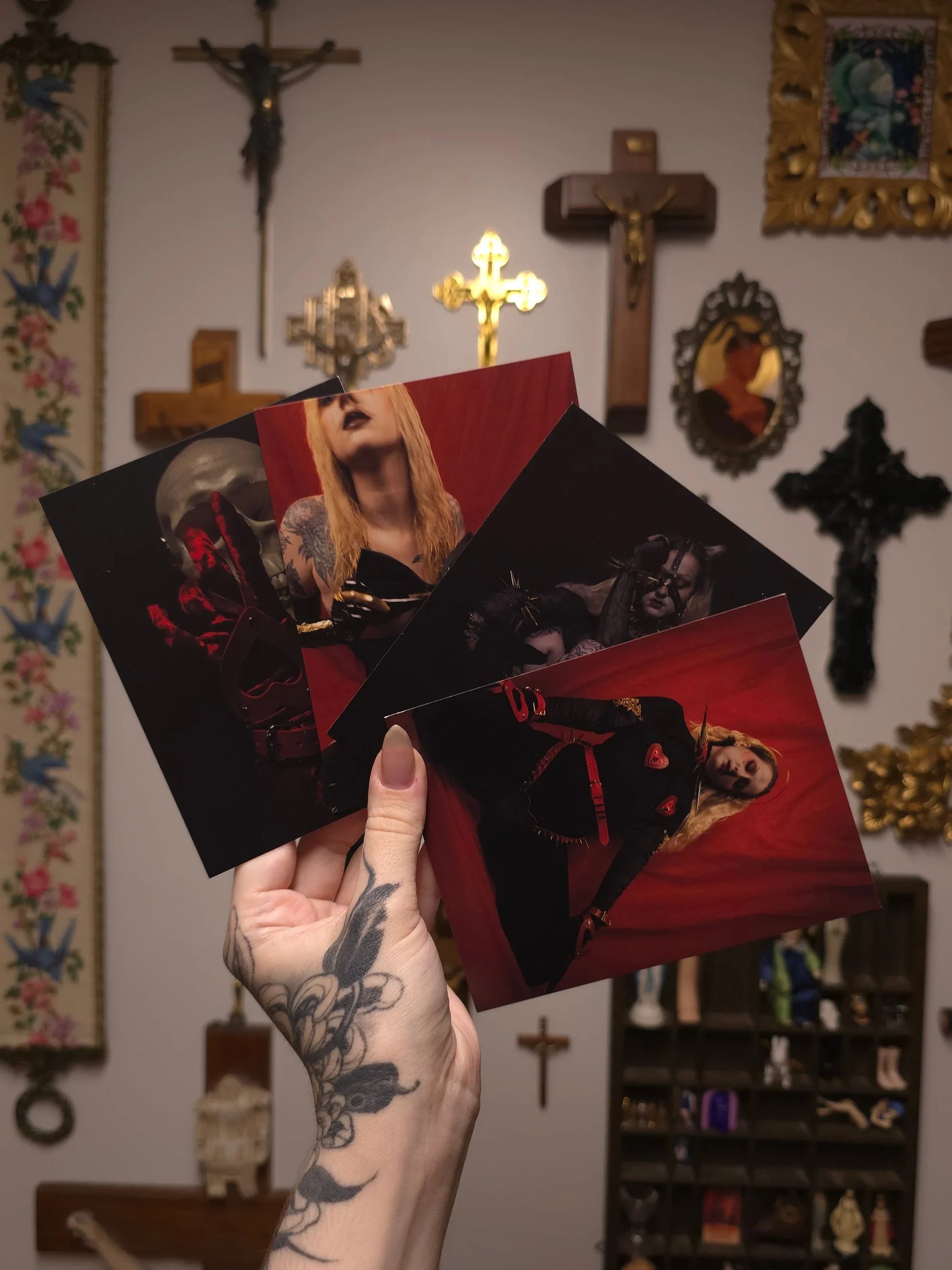hand holding four postcards with portrait prints against a wall with gothic decor
