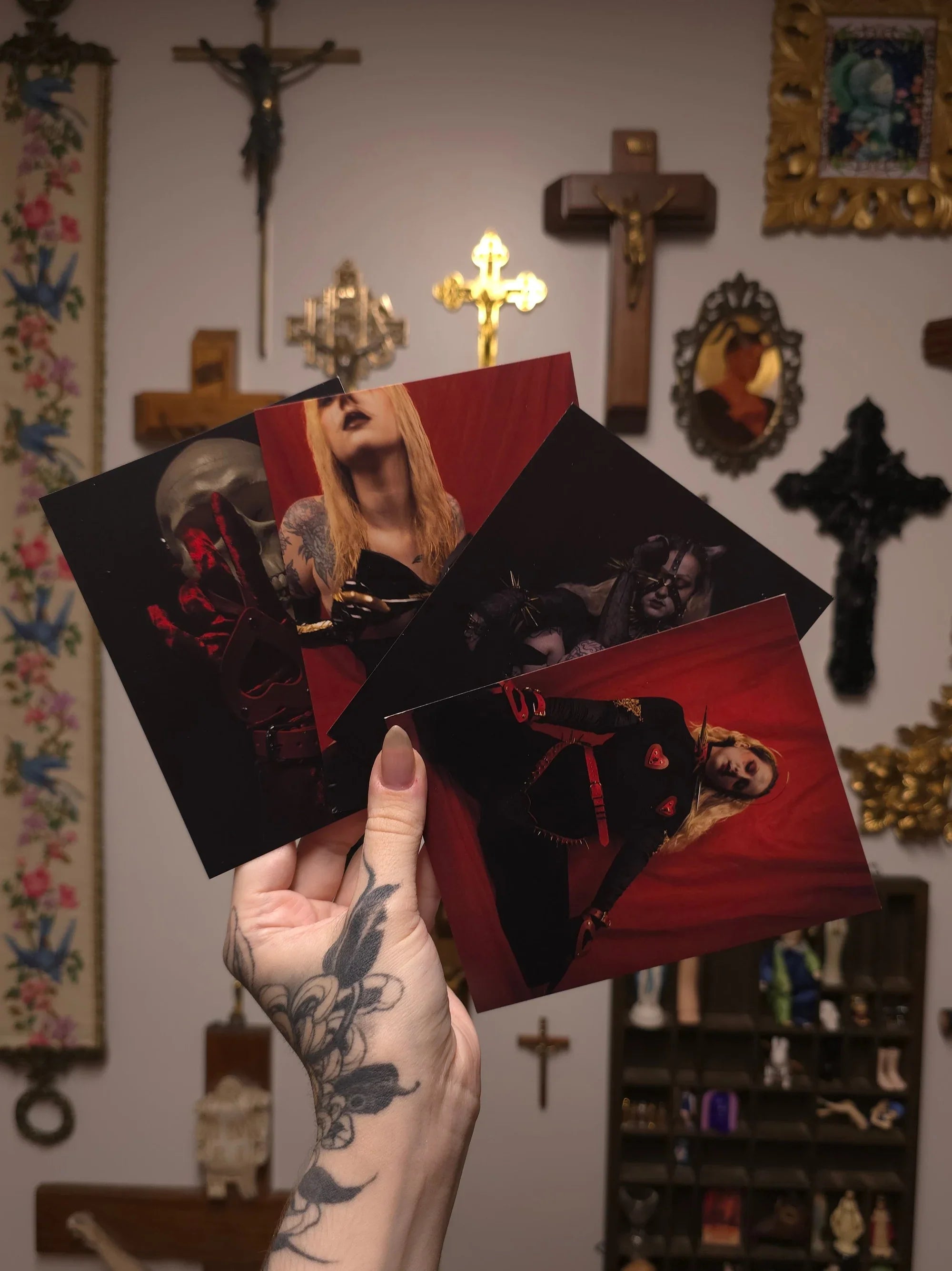 hand holding four postcards with portrait prints against a wall with gothic decor