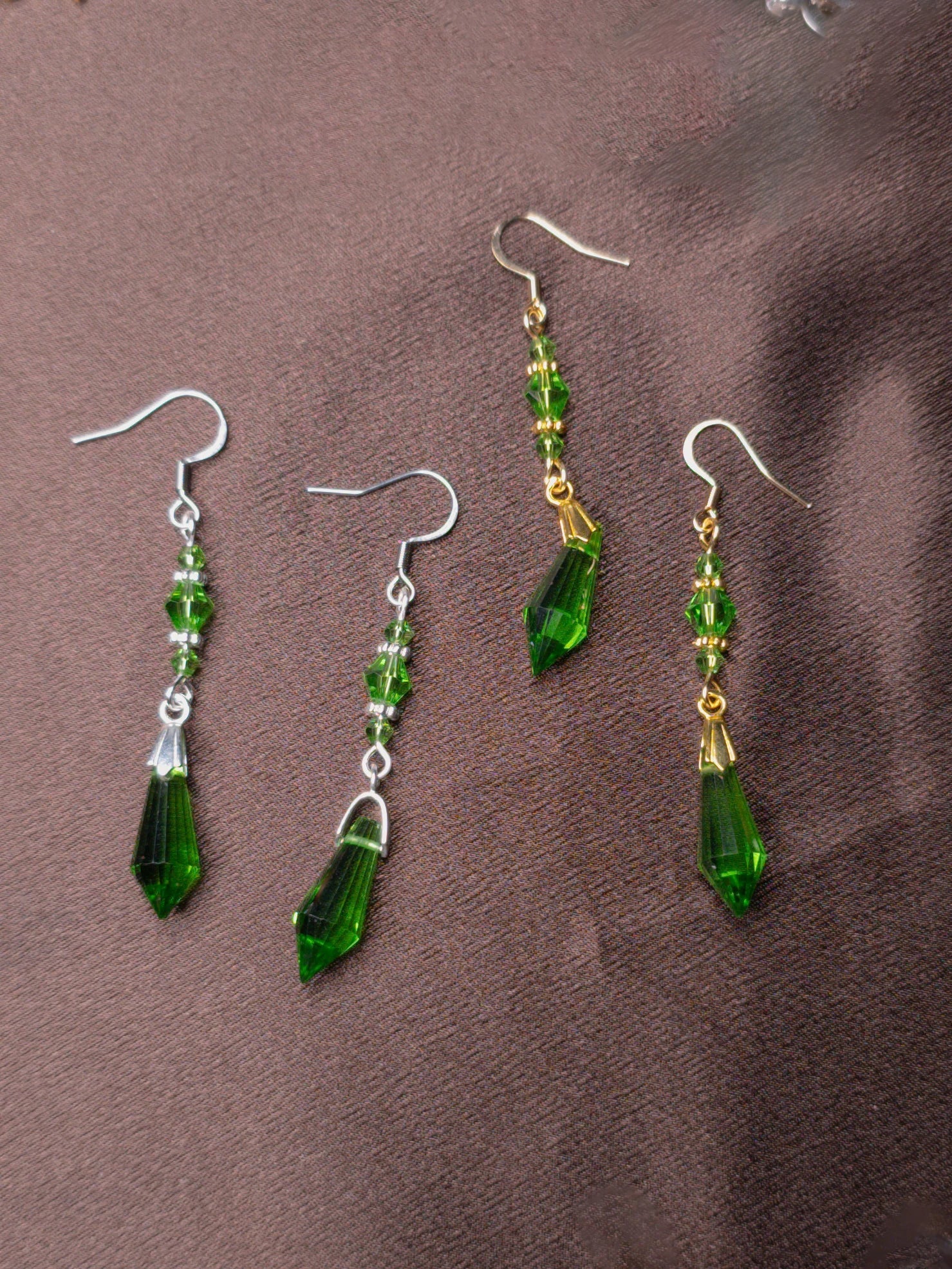 Green glass bead earrings in gold and silver on brown background