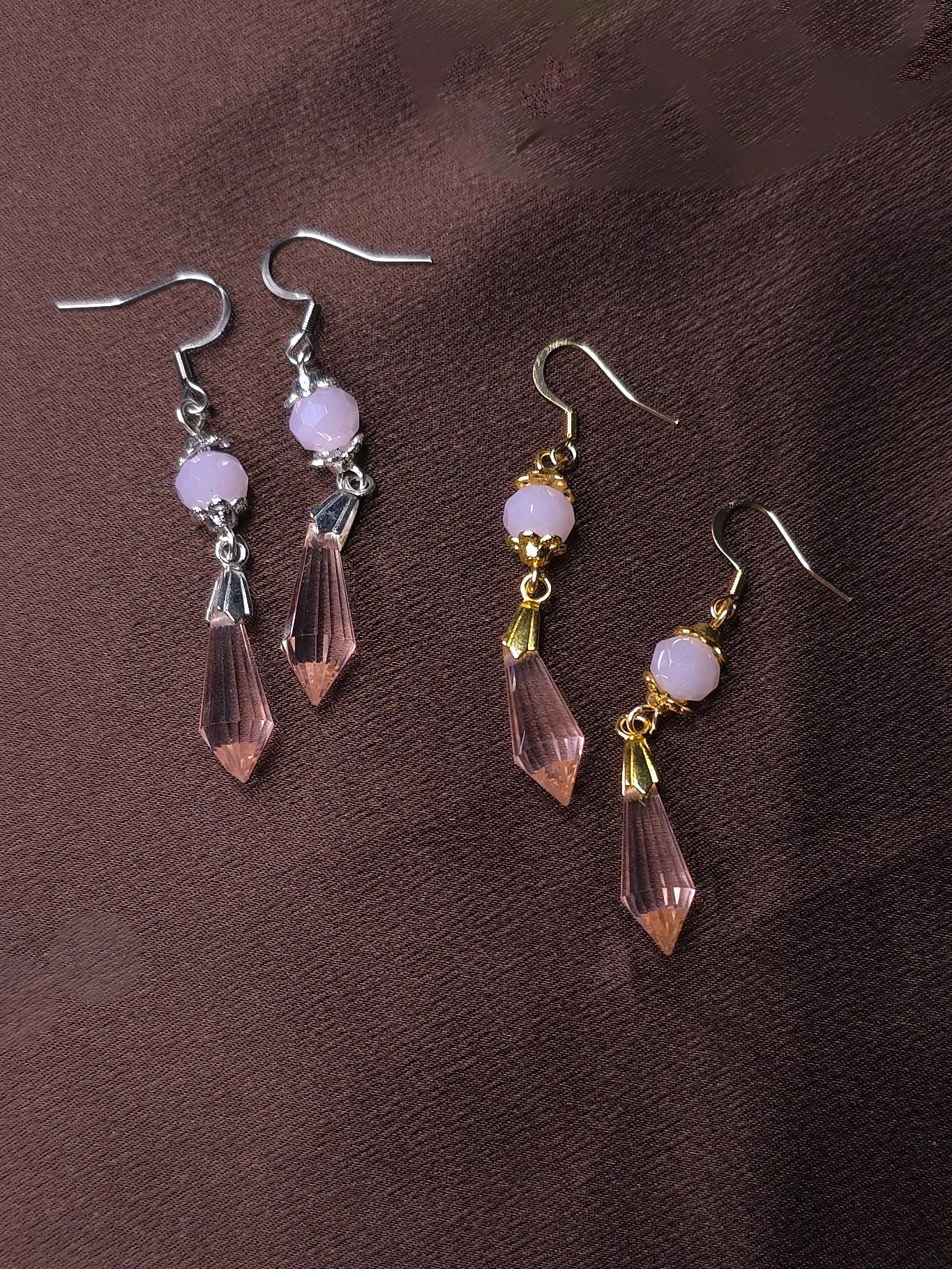 Two pairs of pink earrings on a brown background