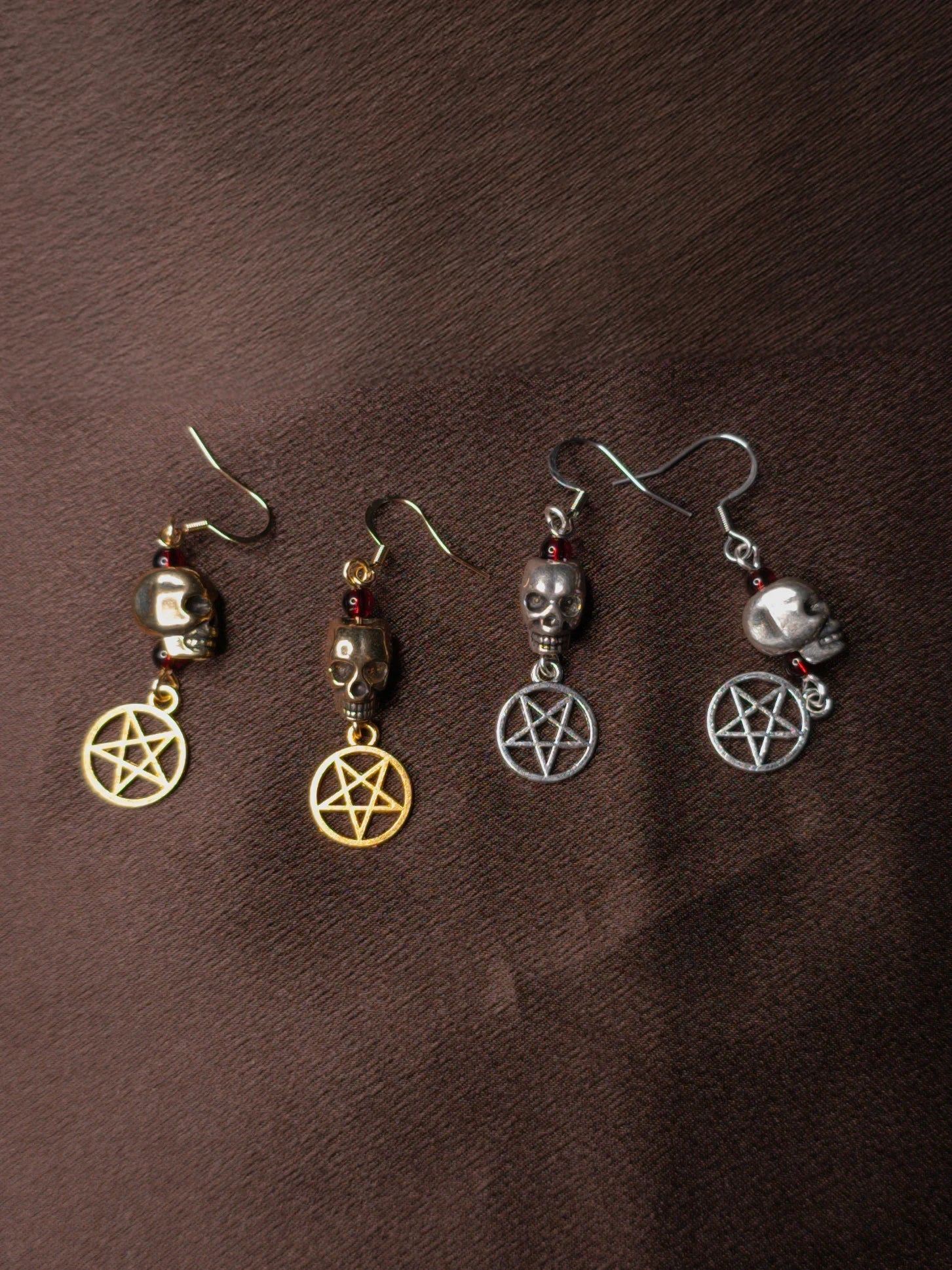 Two pairs of earrings with pentagram charms on a brown surface