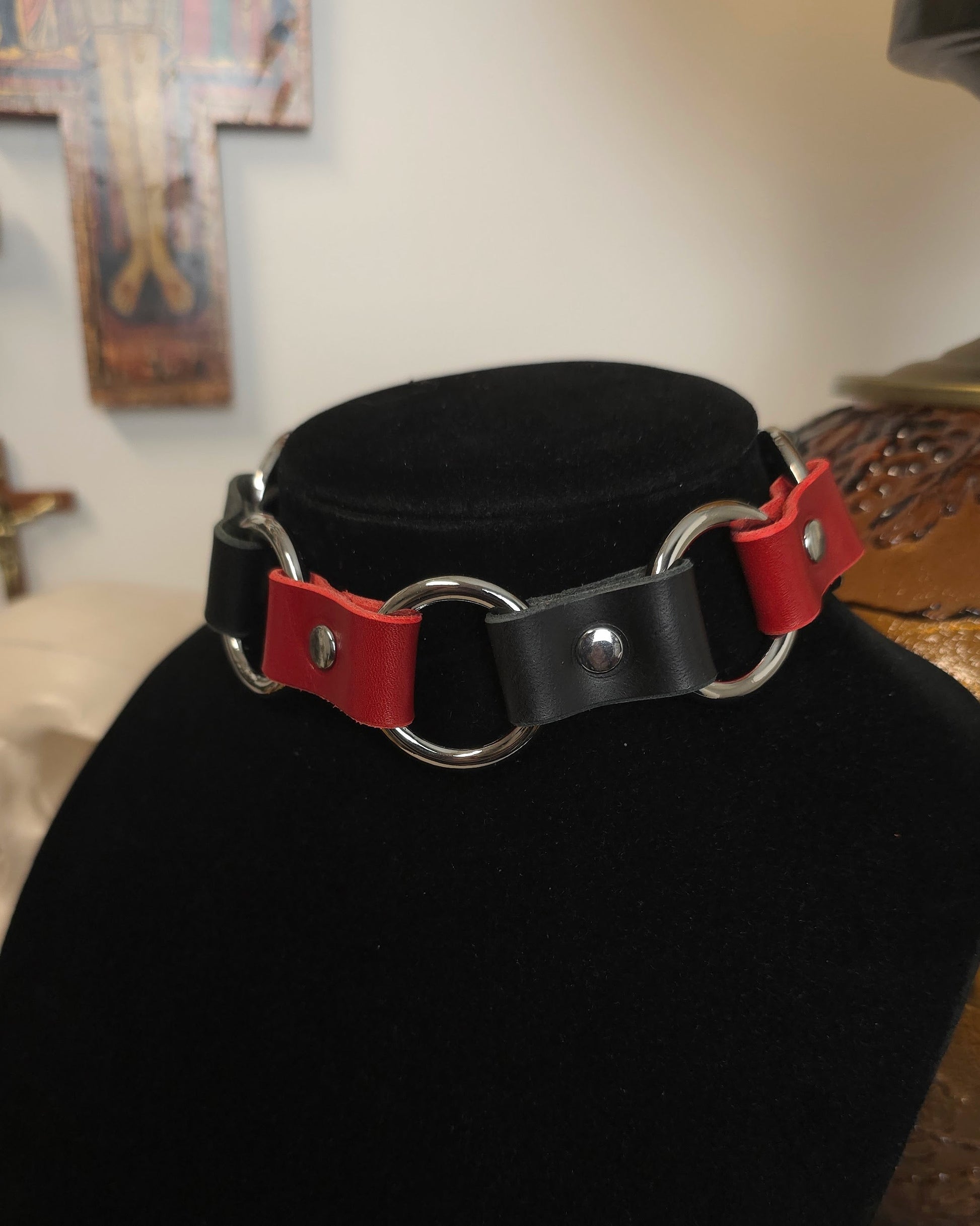 Black and red leather choker on a black mannequin bust with a blurred background