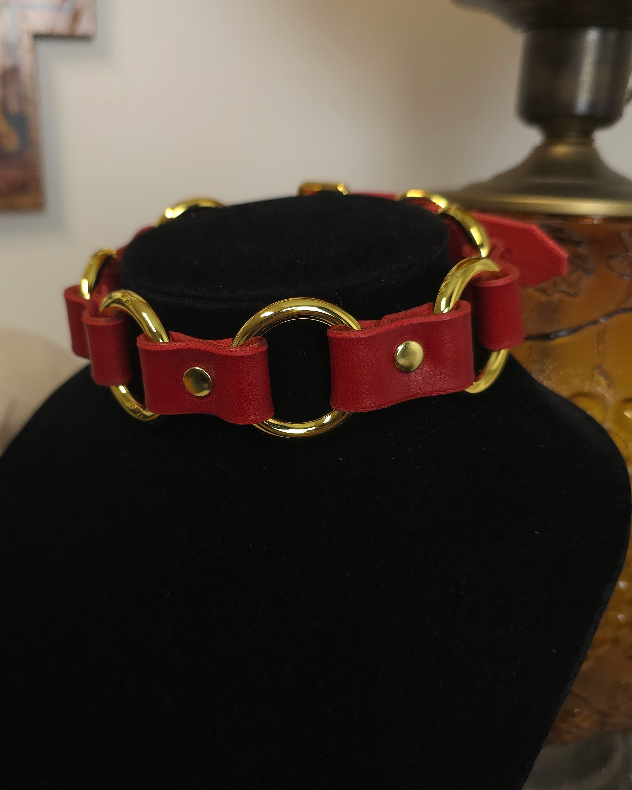 Red leather collar with gold rings on a black stand