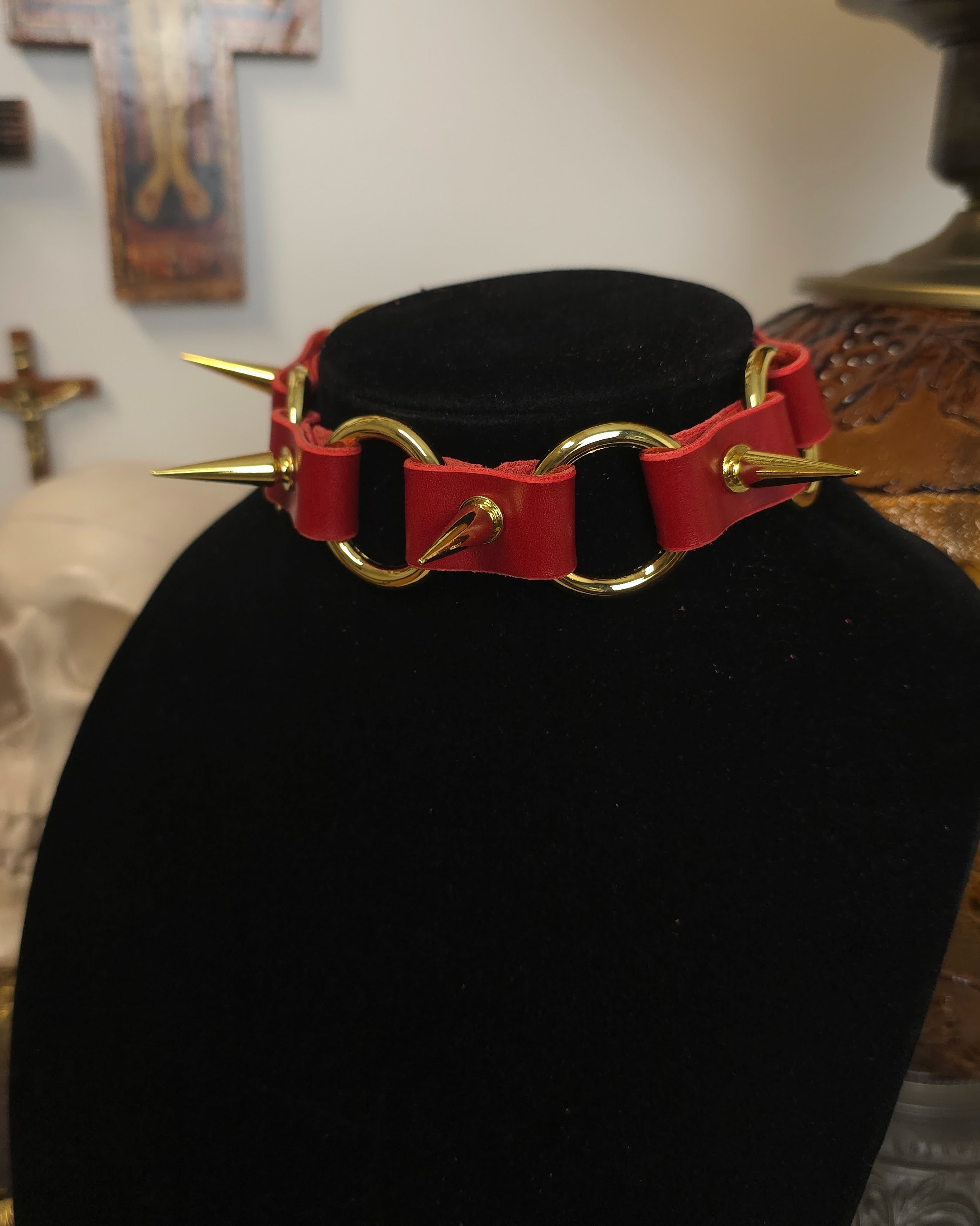 Red leather choker with gold spikes on a black stand