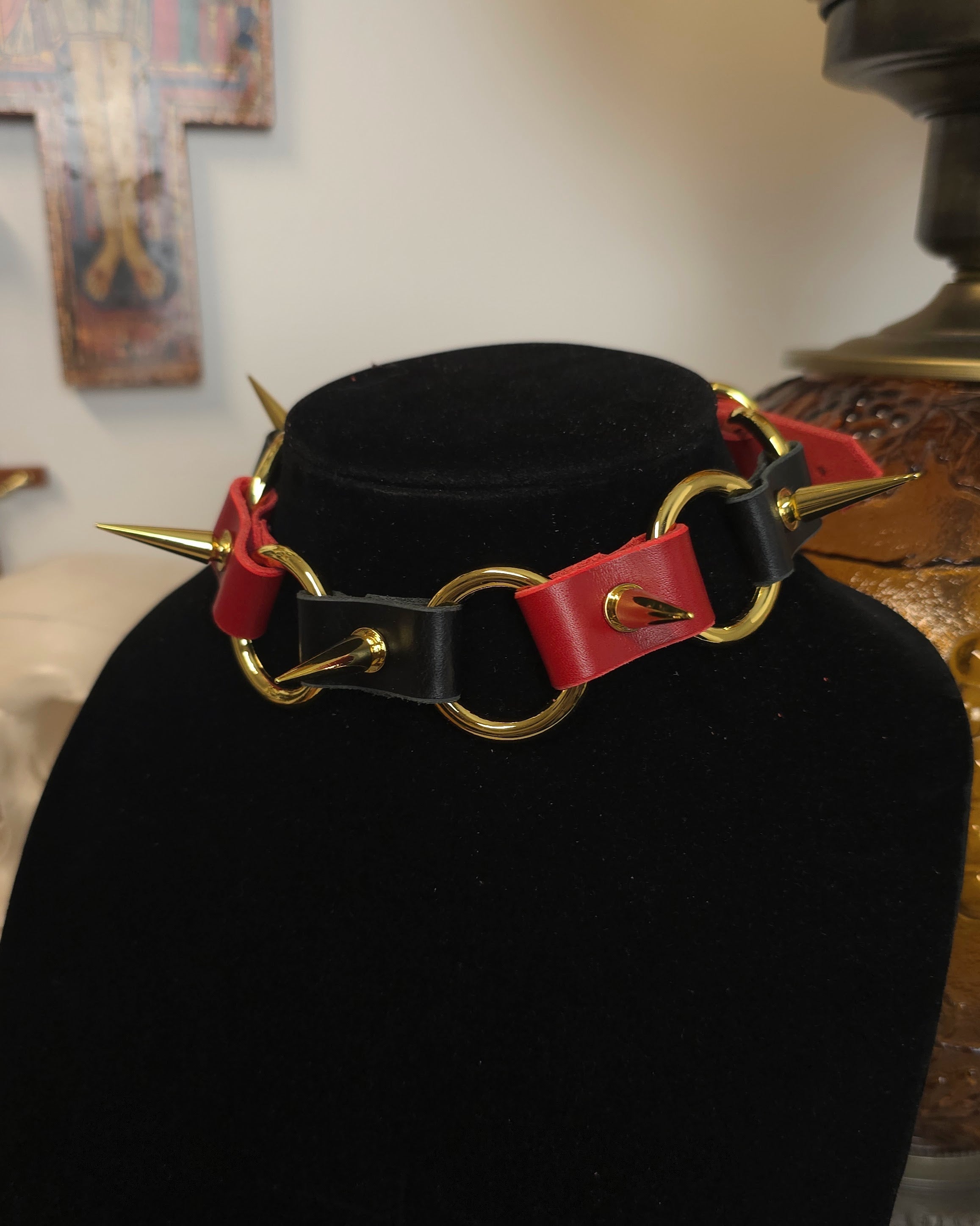 Black choker with red accents and gold spikes on a black stand.