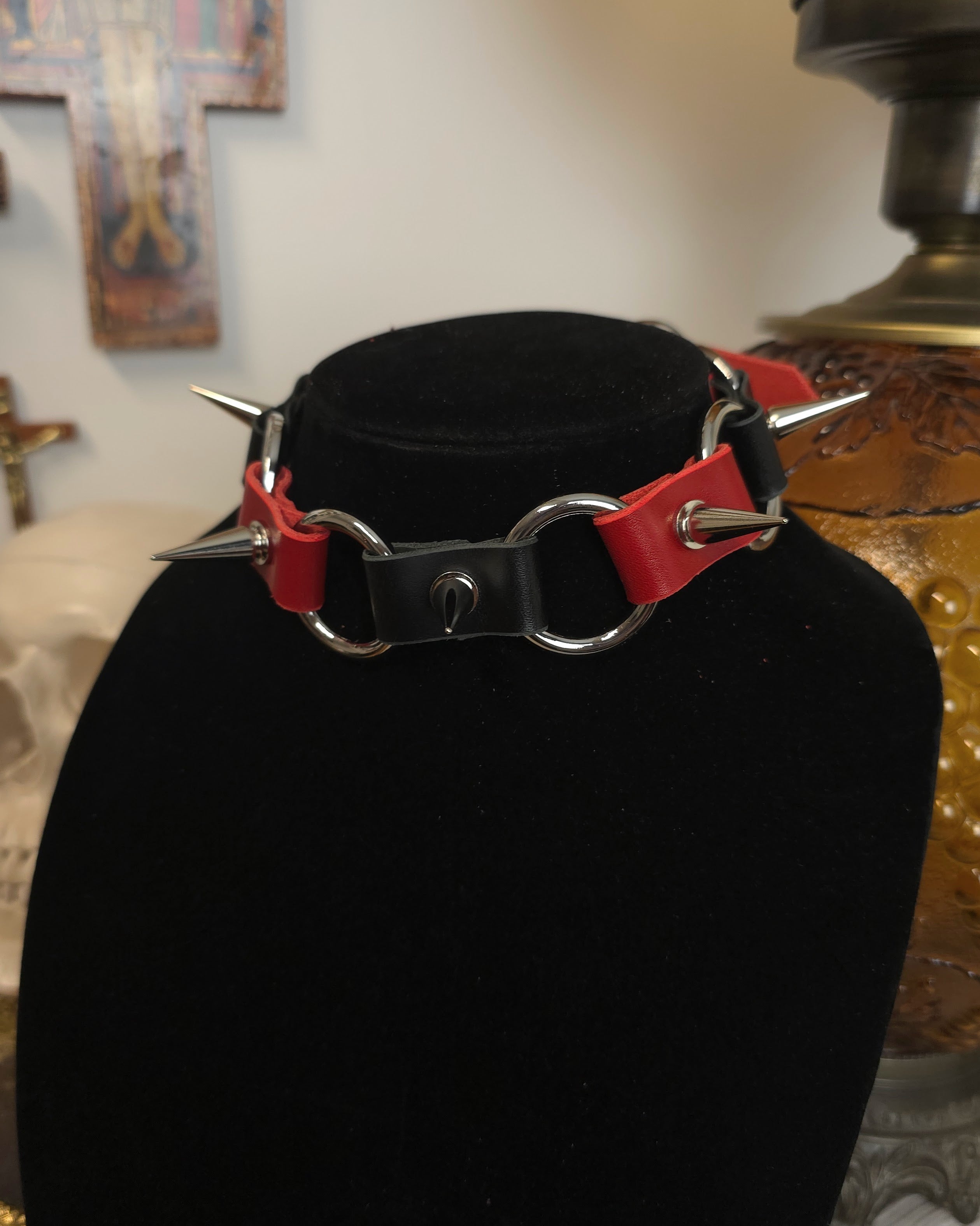 Black choker with red accents and spikes on a black stand against a blurred background