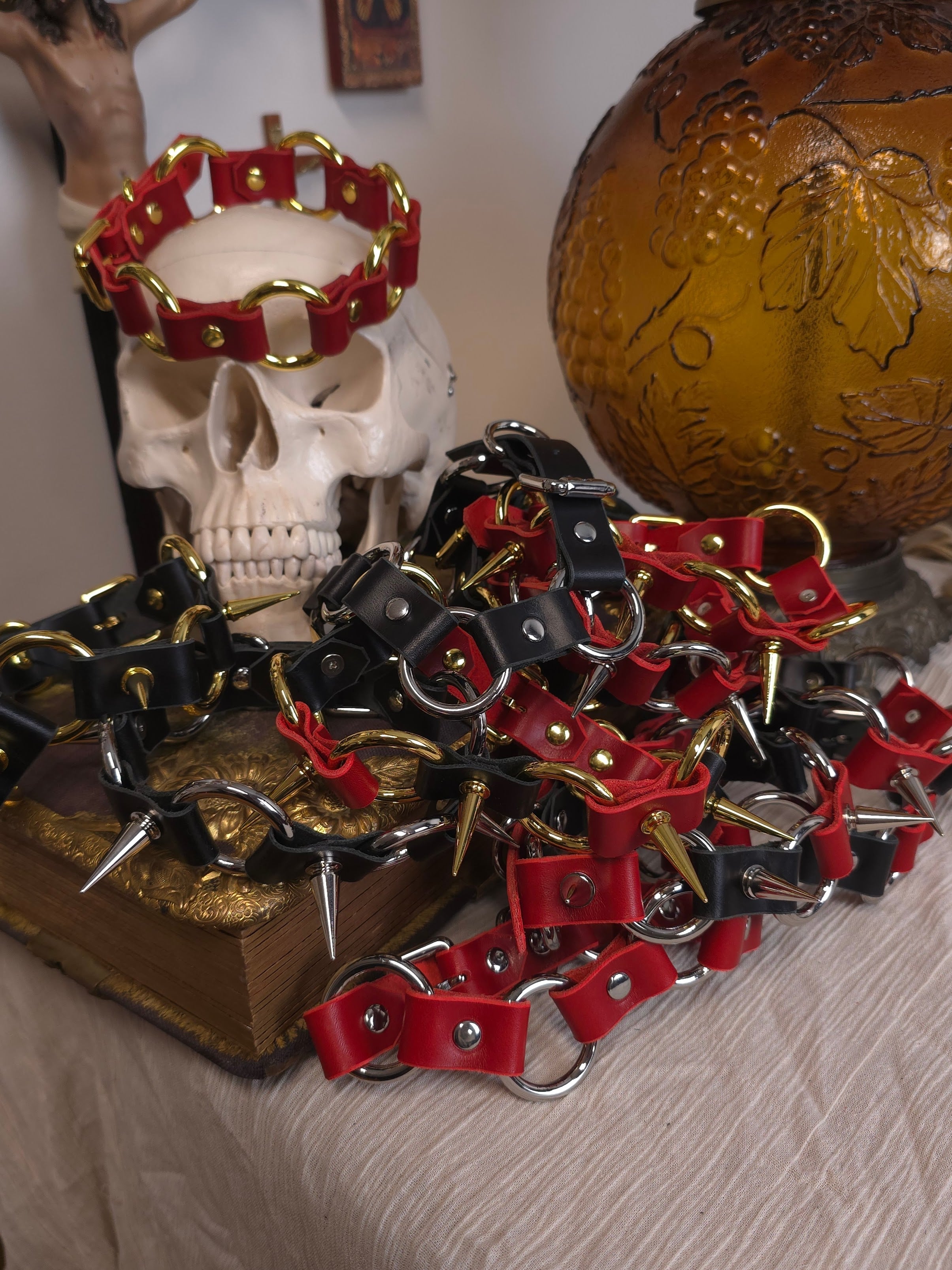 Red and black leather dog collars with metal clasps on a textured surface.
