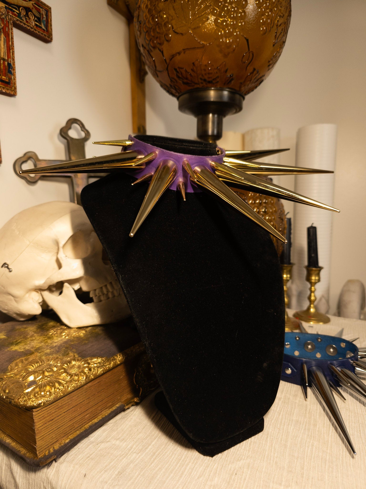 Purple and gold spiked collar on black necklace display with gothic decor