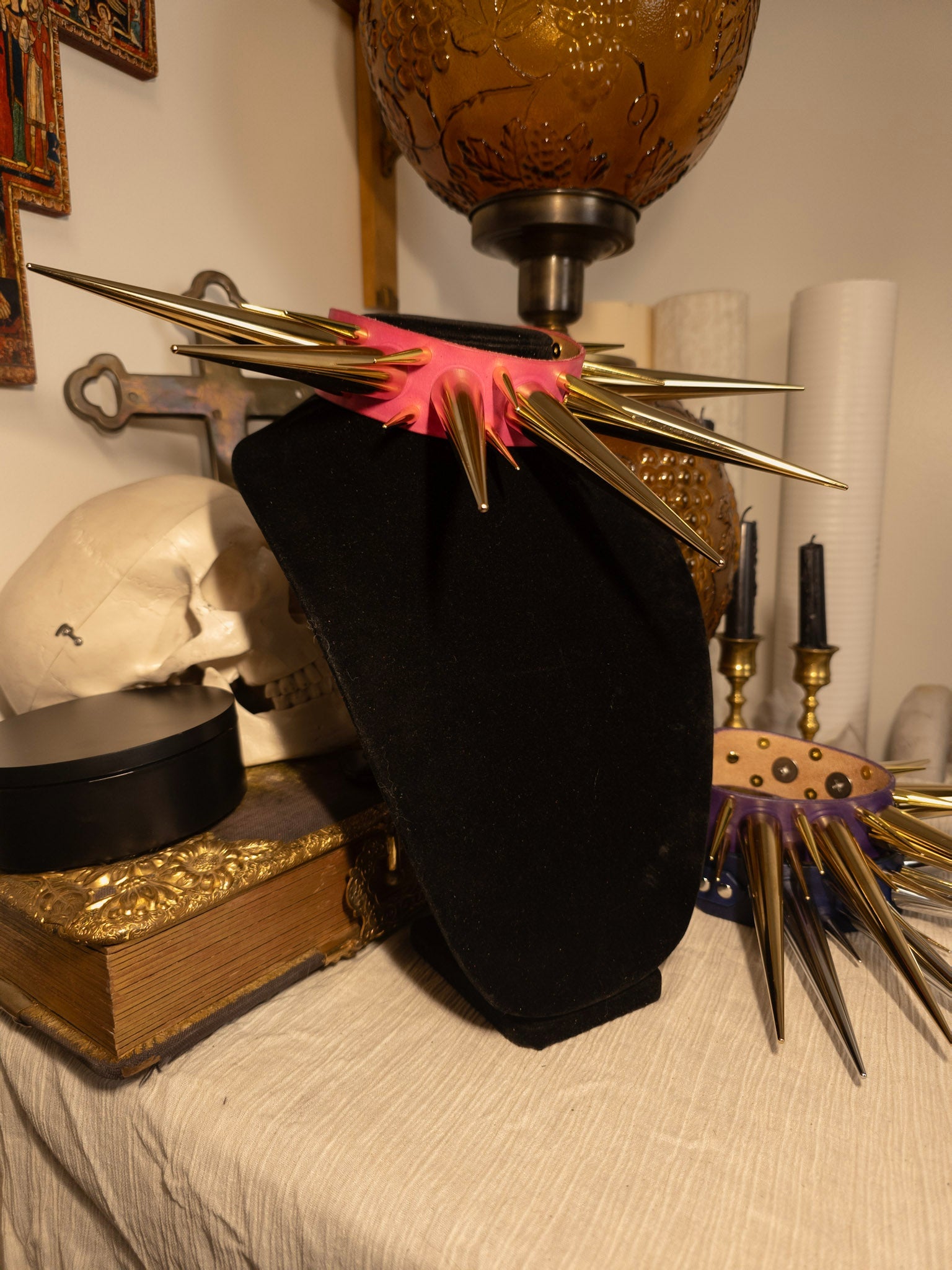 pink and gold spiked collar on black necklace display with gothic decor