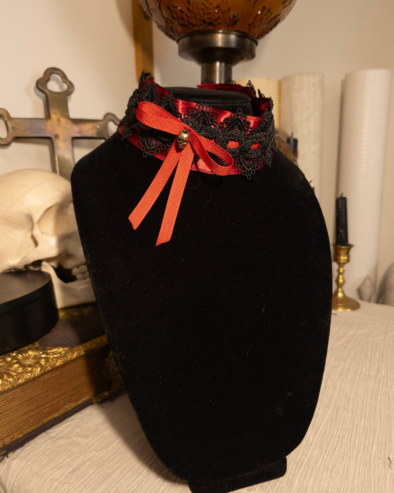 red and black ribbon choker on a black necklace display against gothic decor
