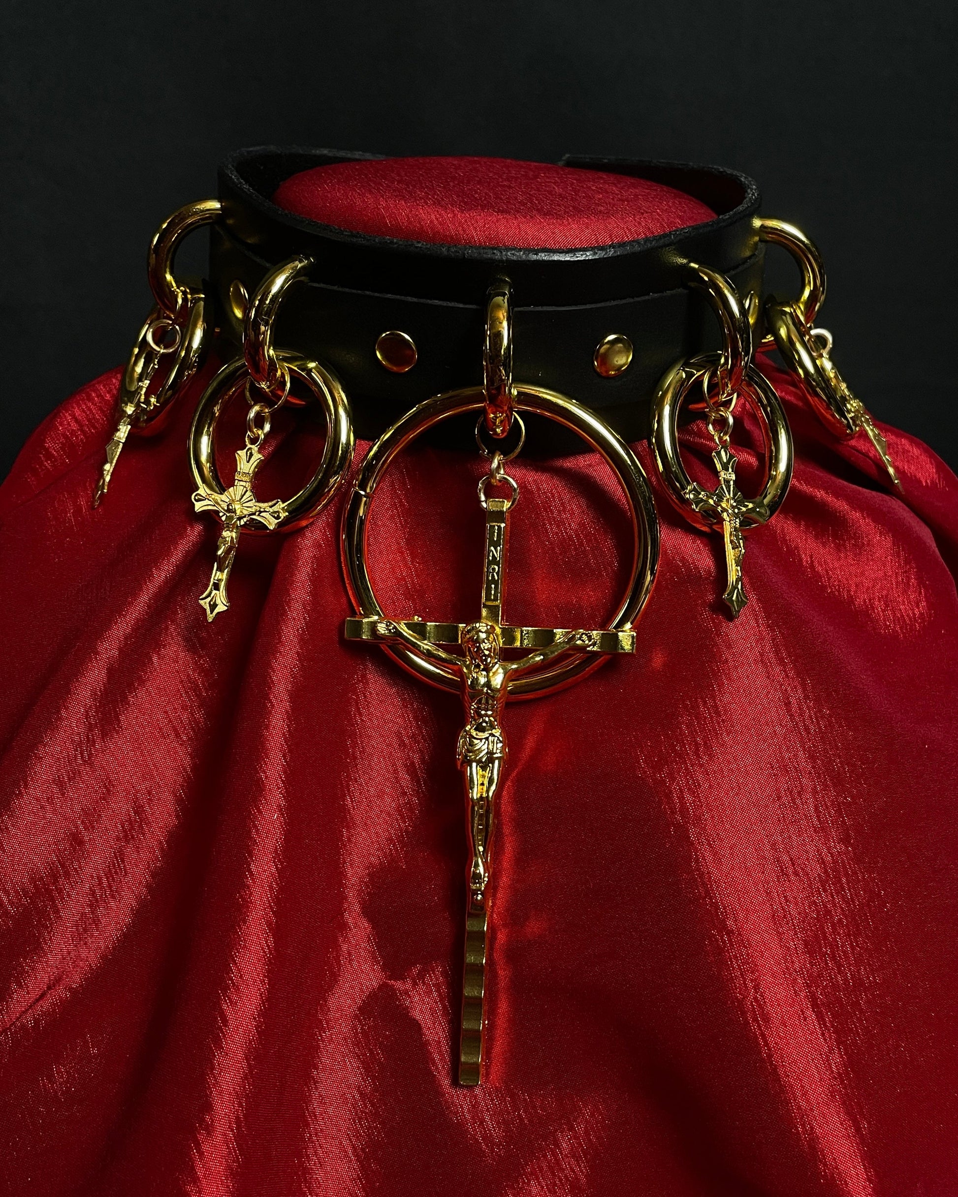 Decorative collar with gold rings and cross pendant on a red fabric background