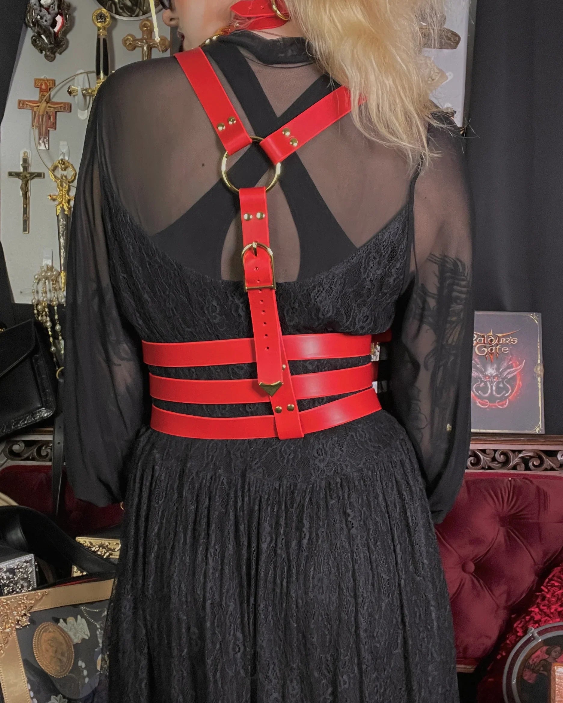 Person wearing a black dress with a red harness in a decorative setting