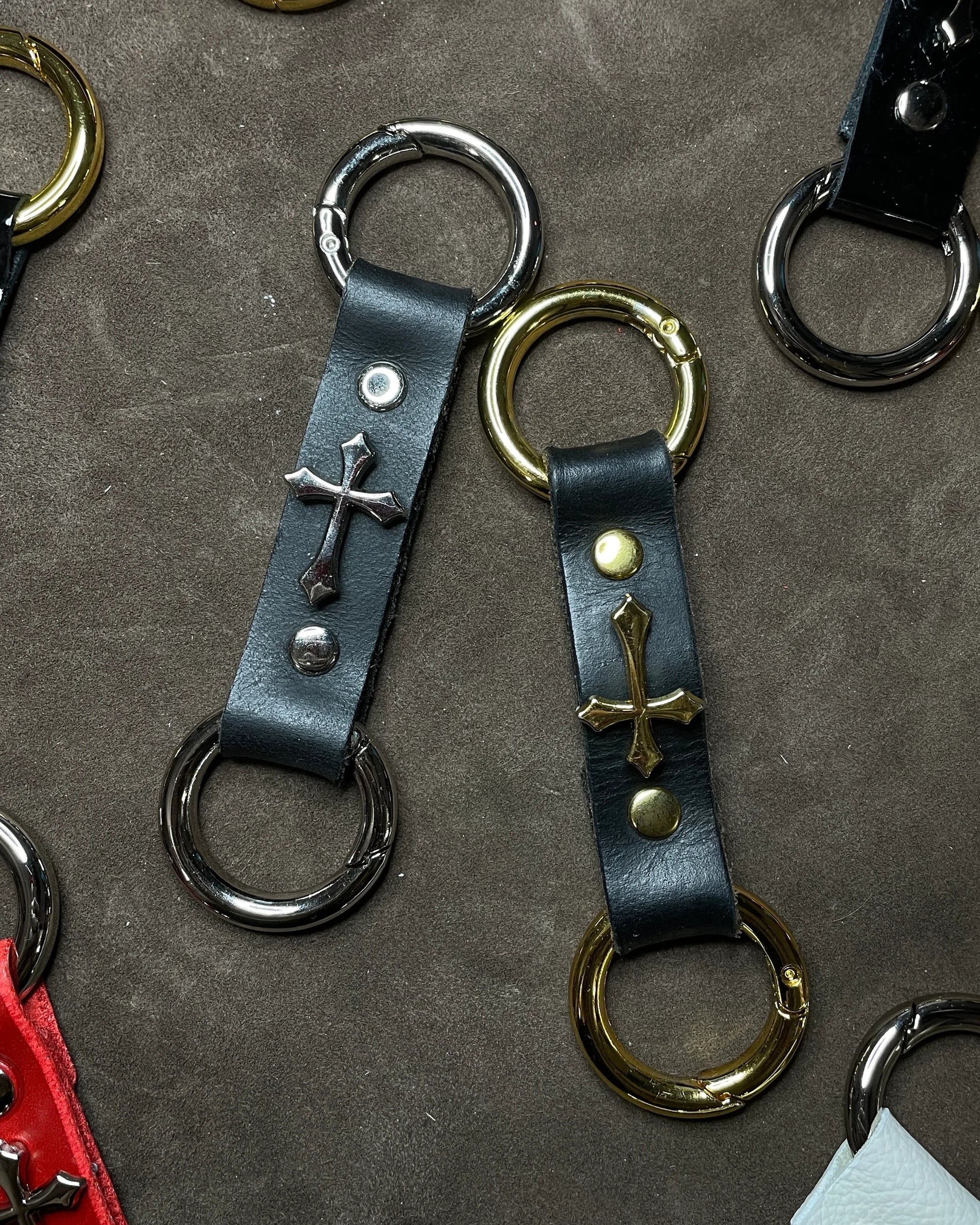 Leather keychains with metal rings and cross designs on a textured surface