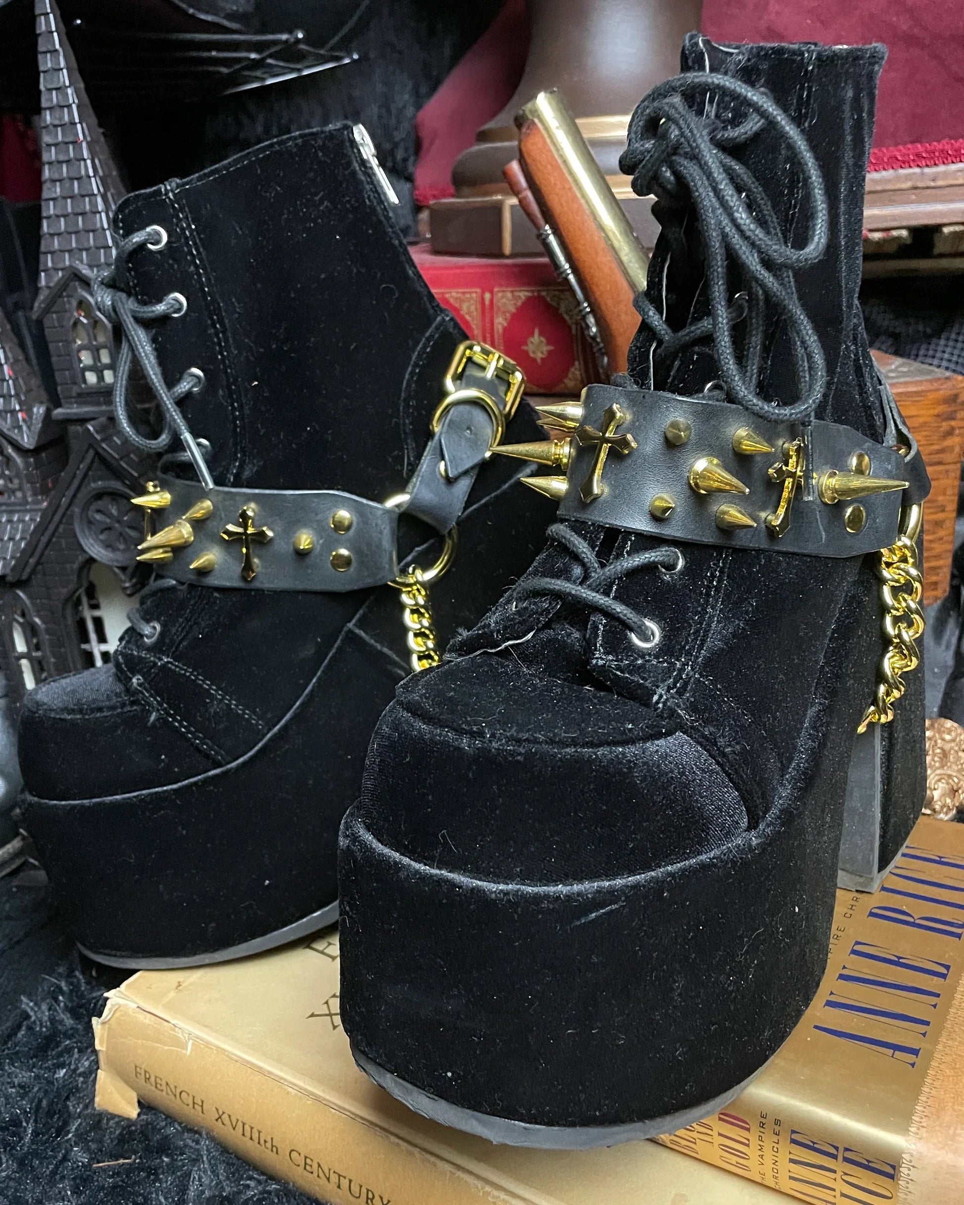 a pair of black velvet boots with black leather and gold spike belts