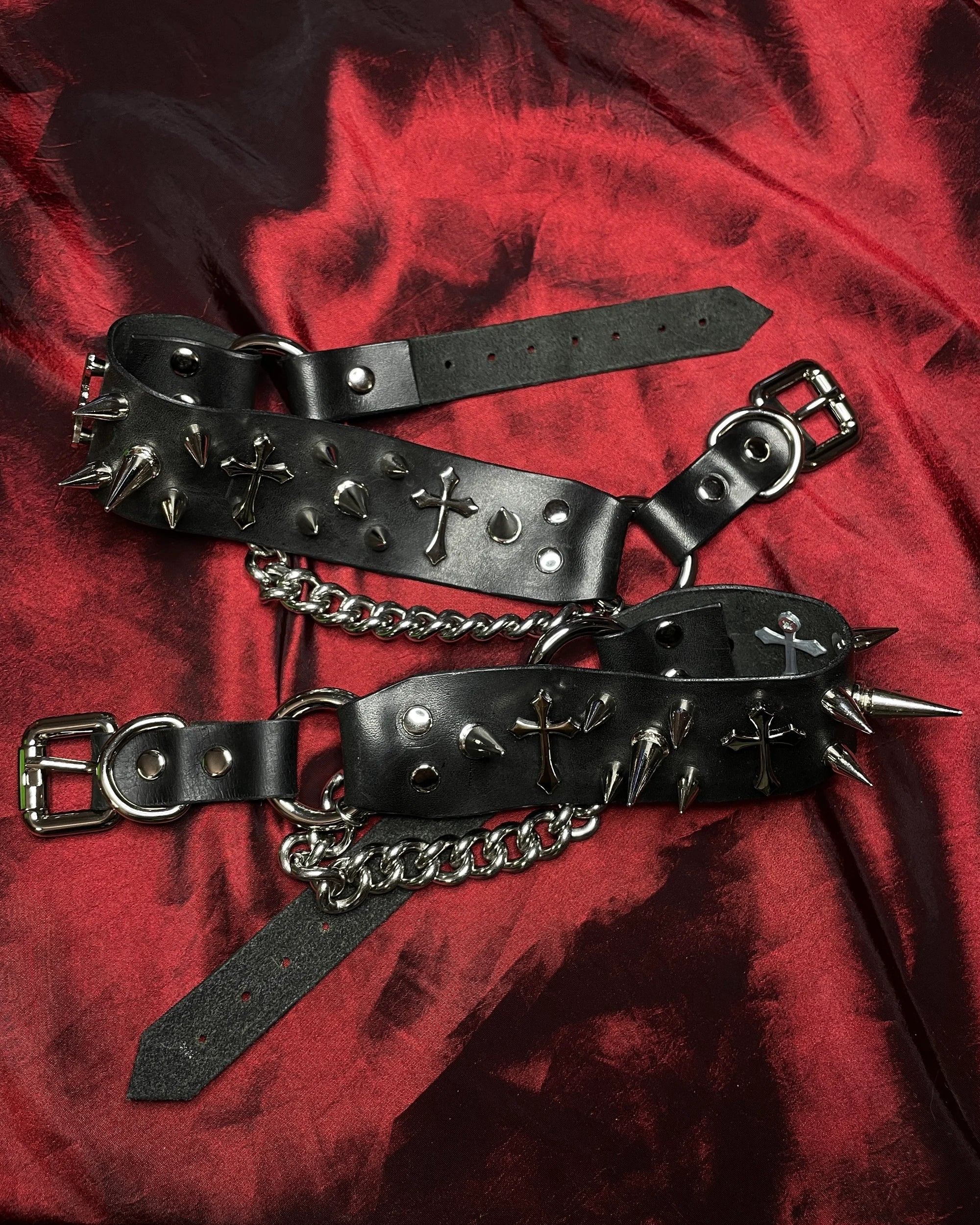black leather shoe belts laid on red background