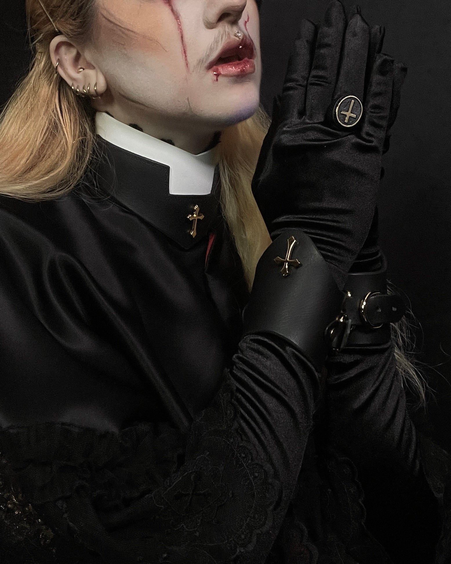 Person in black clothing with gloves, in prayer on a dark background