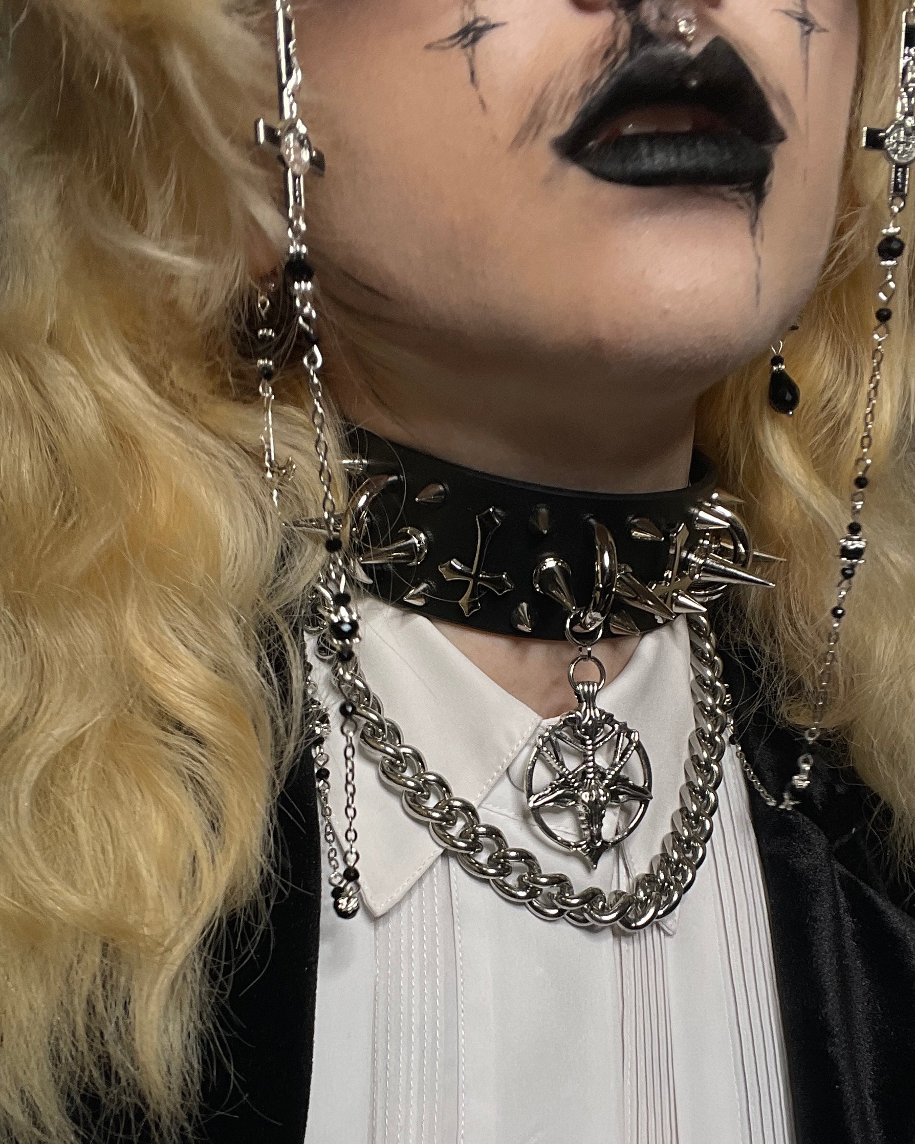 Person wearing a black choker with chain accessories and blonde hair.