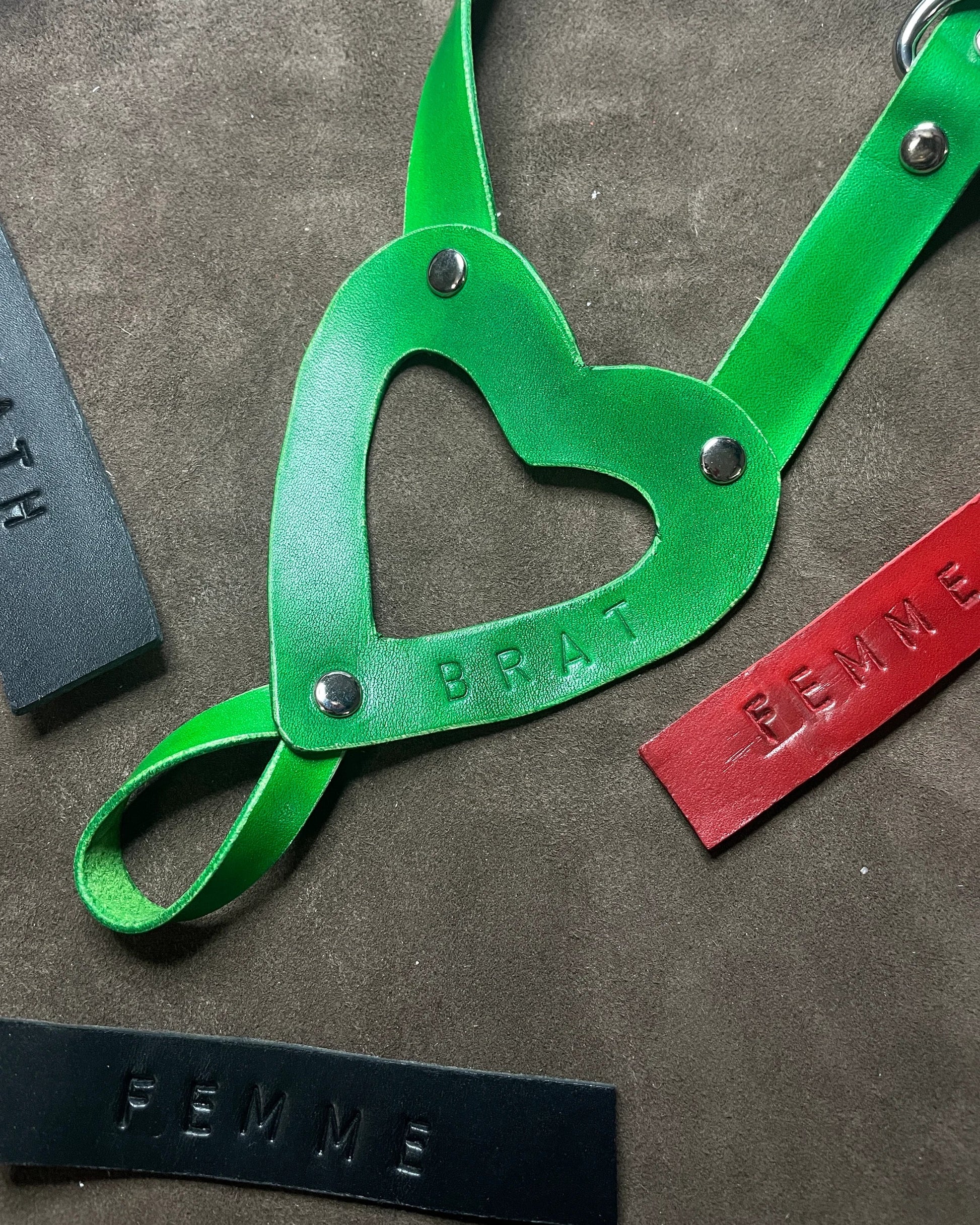 Green leather strap with heart-shaped cutout on a textured surface