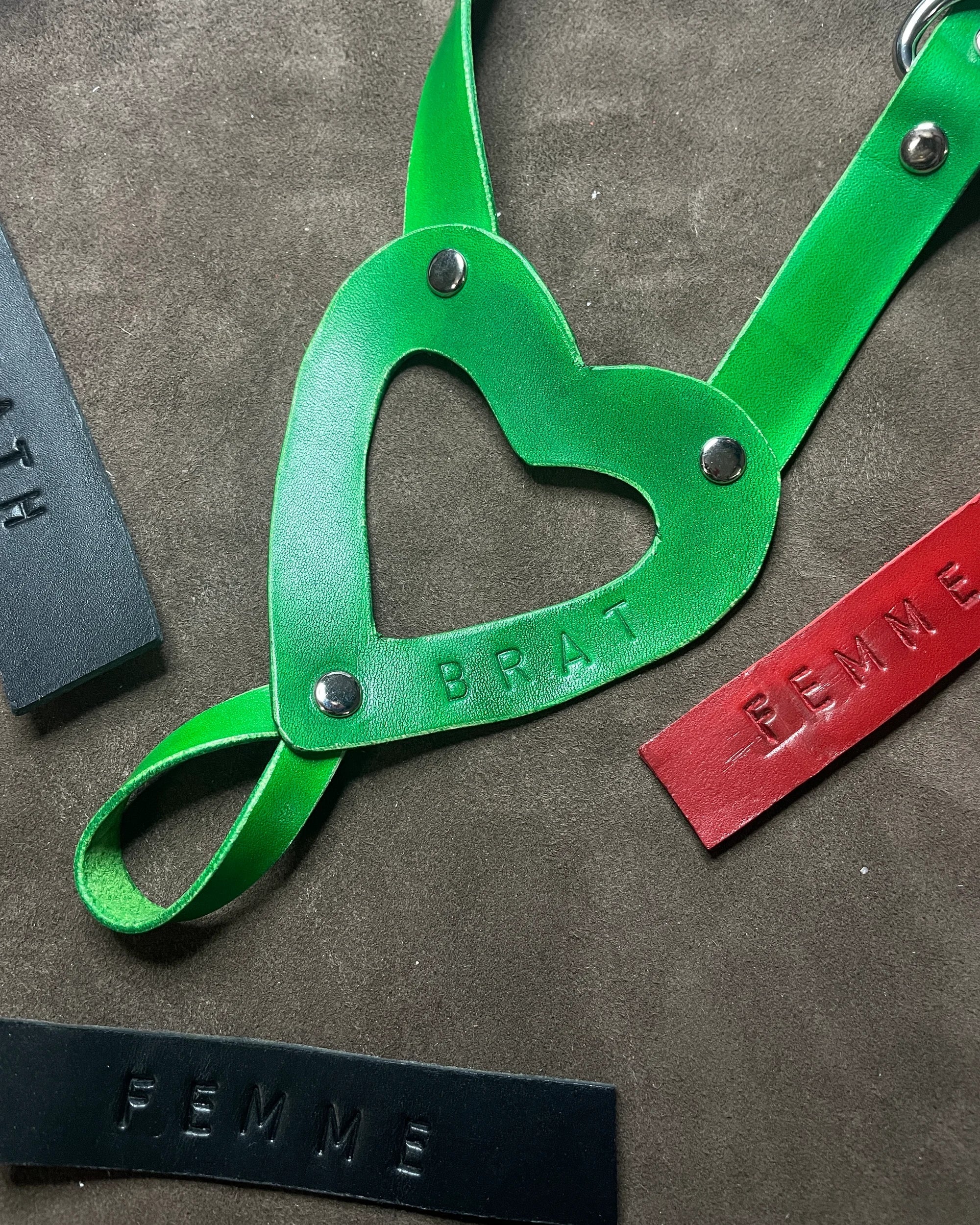 Green leather strap with heart-shaped cutout on a textured surface
