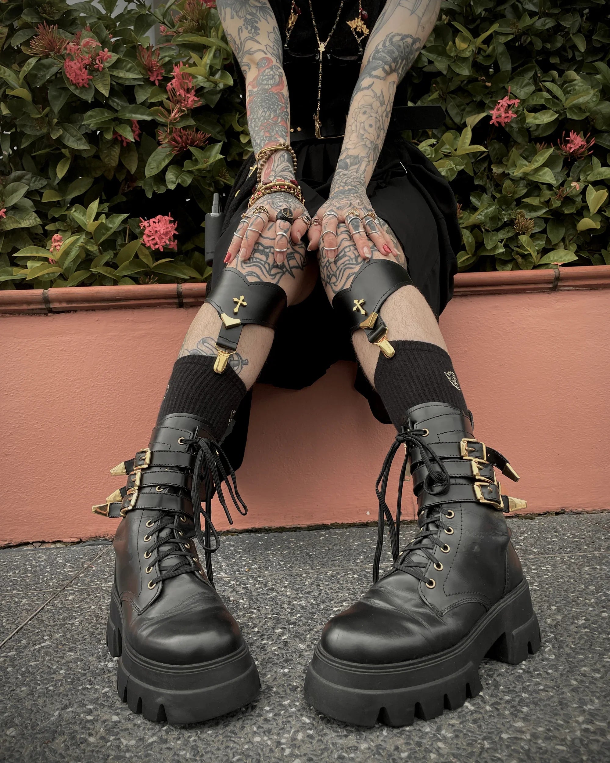 Person wearing black boots and black leather sock garters with hands on knees.