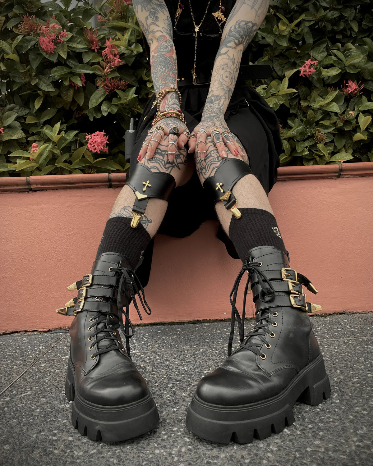 Person wearing black boots and black leather sock garters with hands on knees.