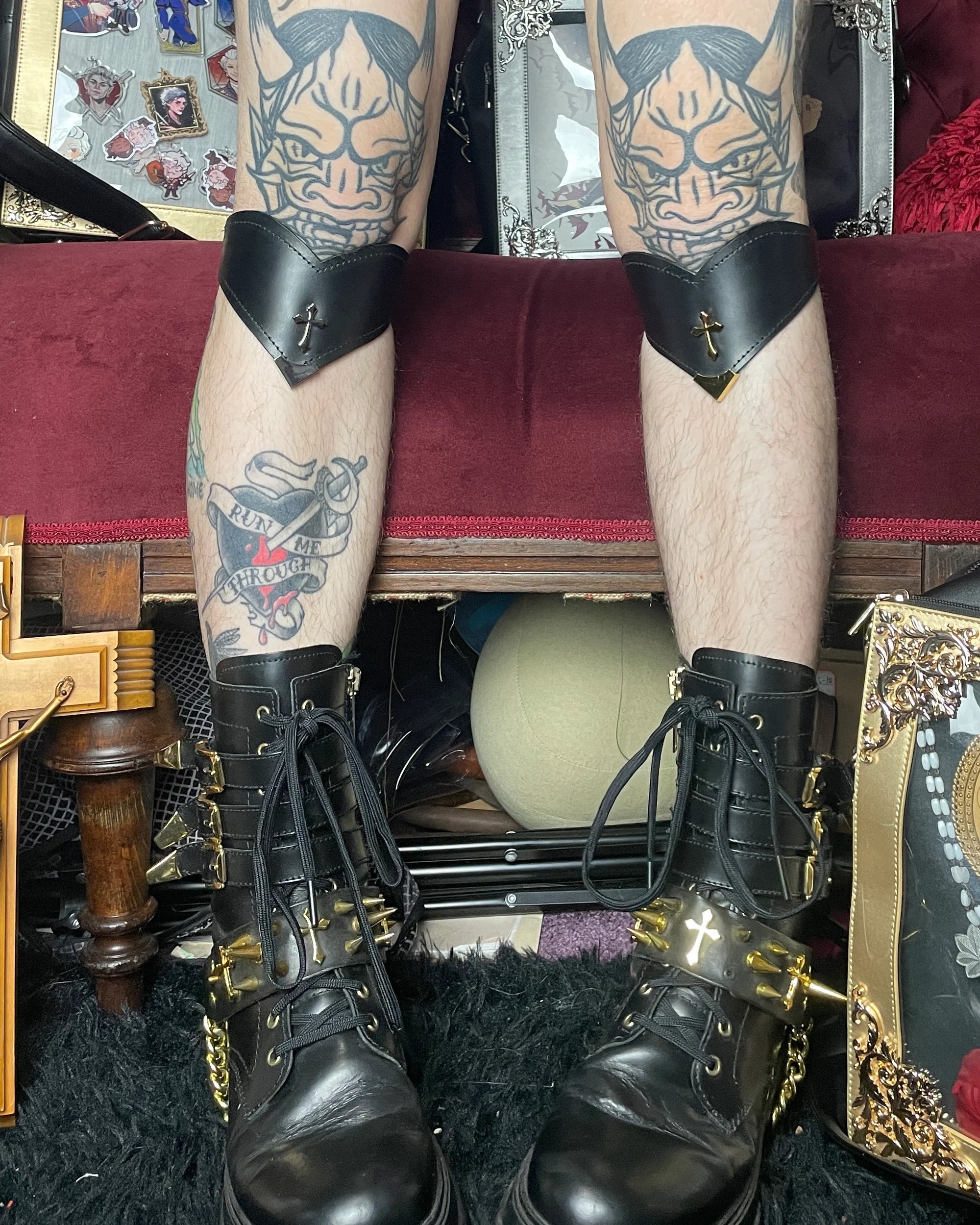 photo of legs with tattoos, wearing black boots and black leather cuffs below knees