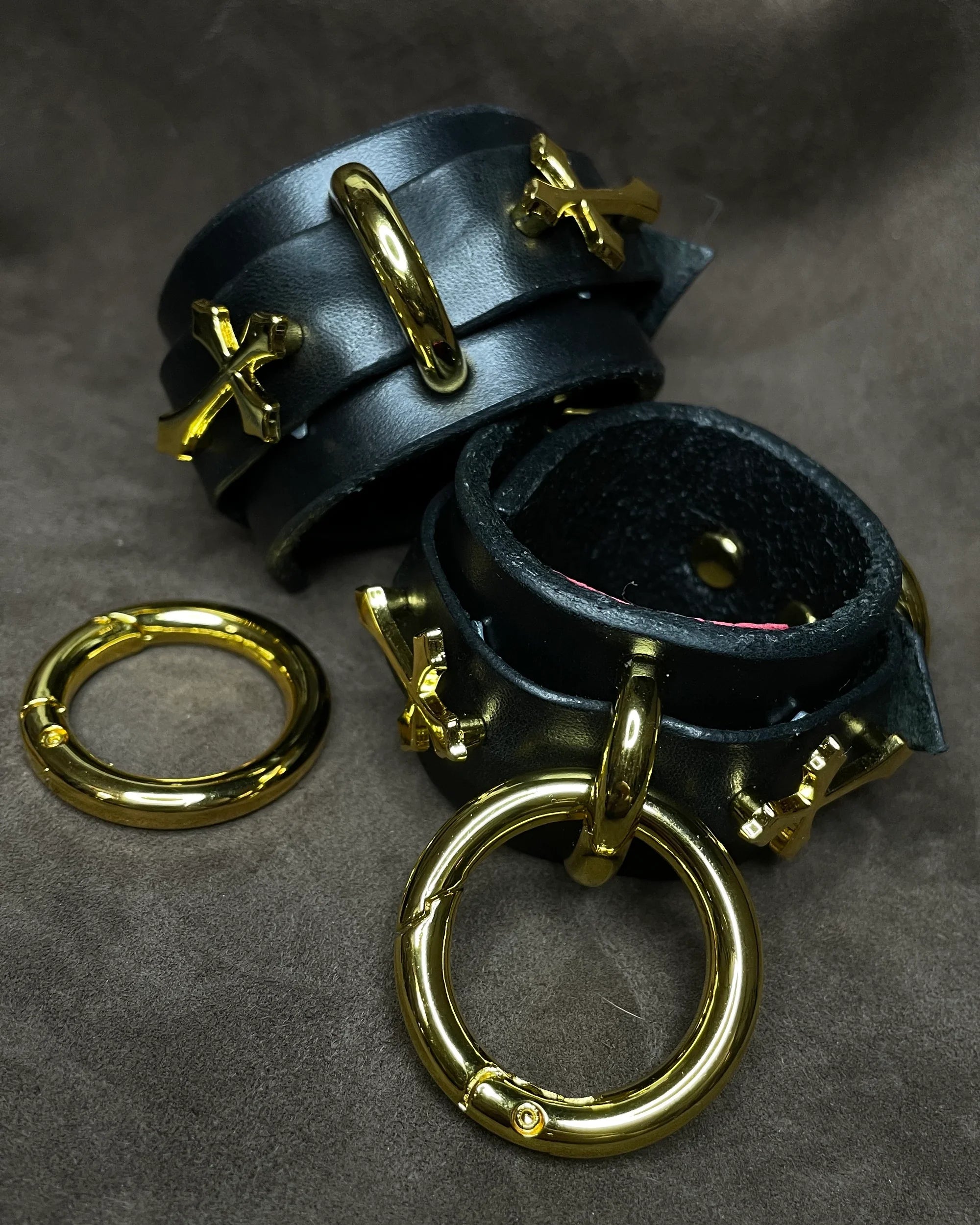 Black leather cuffs with gold hardware on a dark gray background