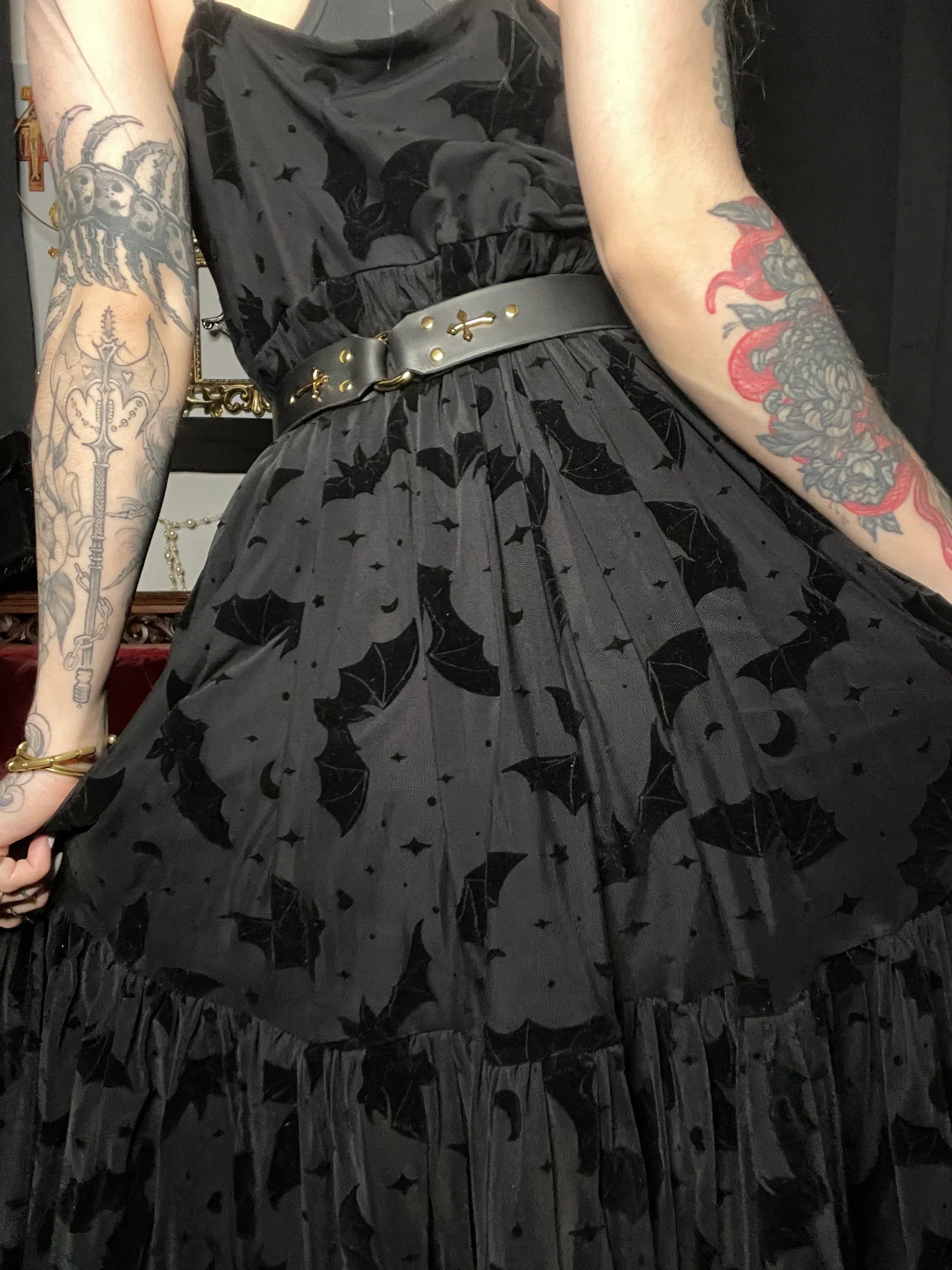 person wearing black bat patterned dress showing off back of belt