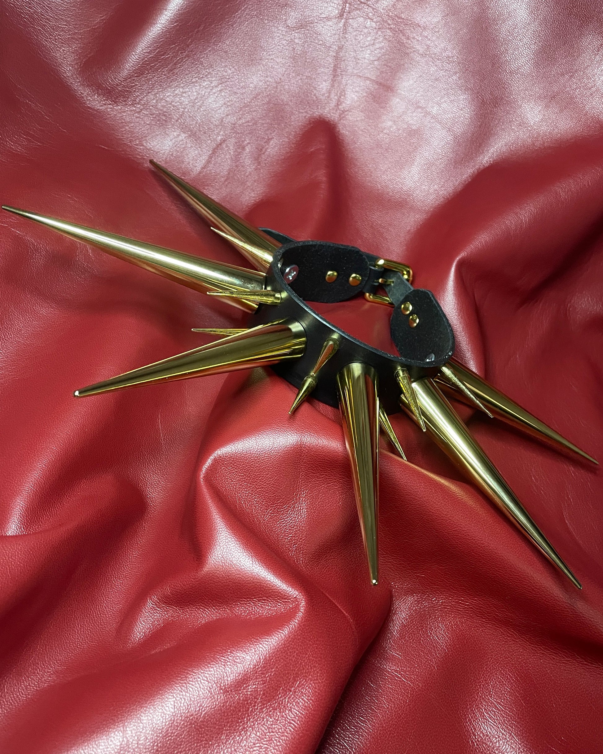 Gold spiked collar on a red leather surface