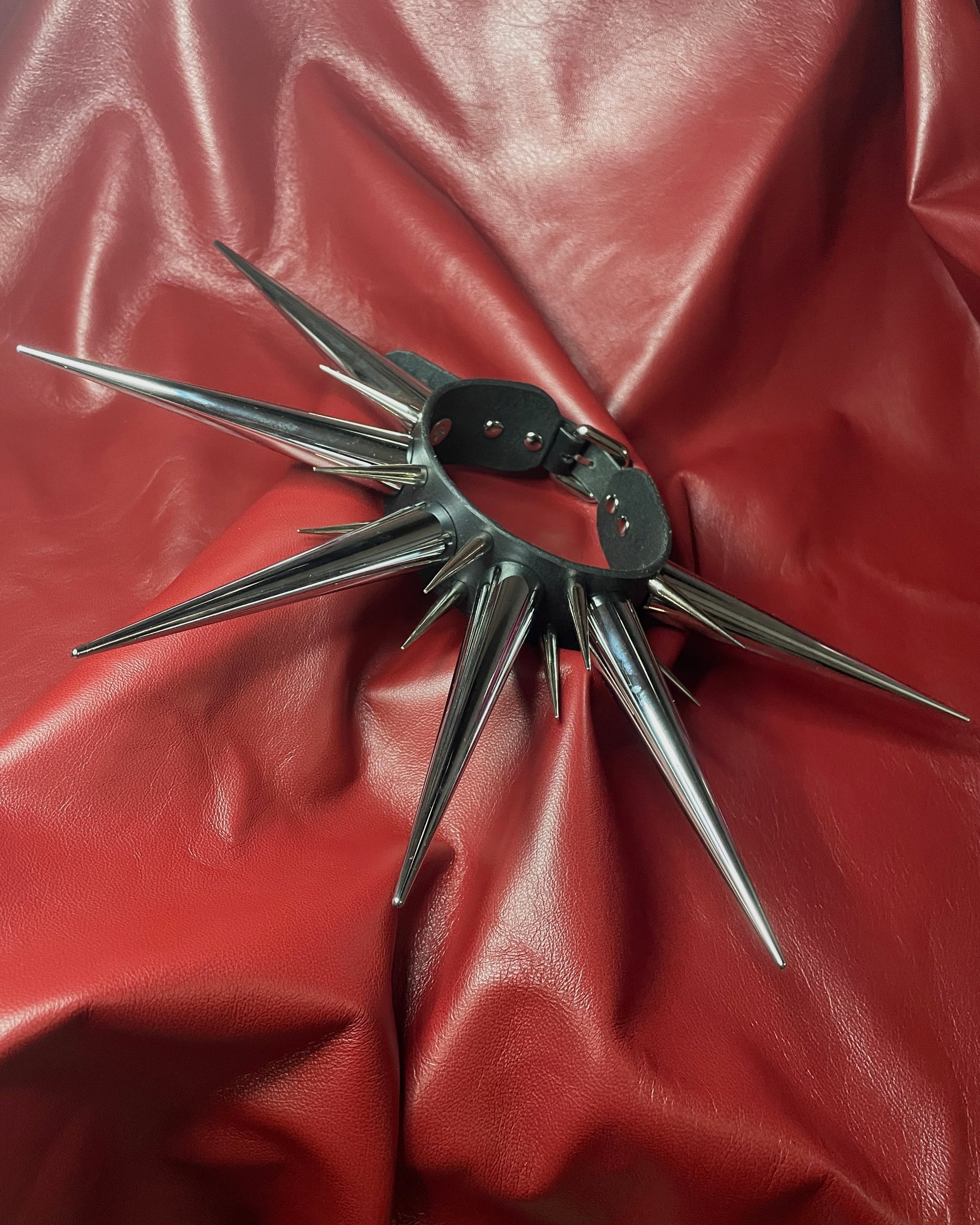 Spiked leather collar on a red leather background