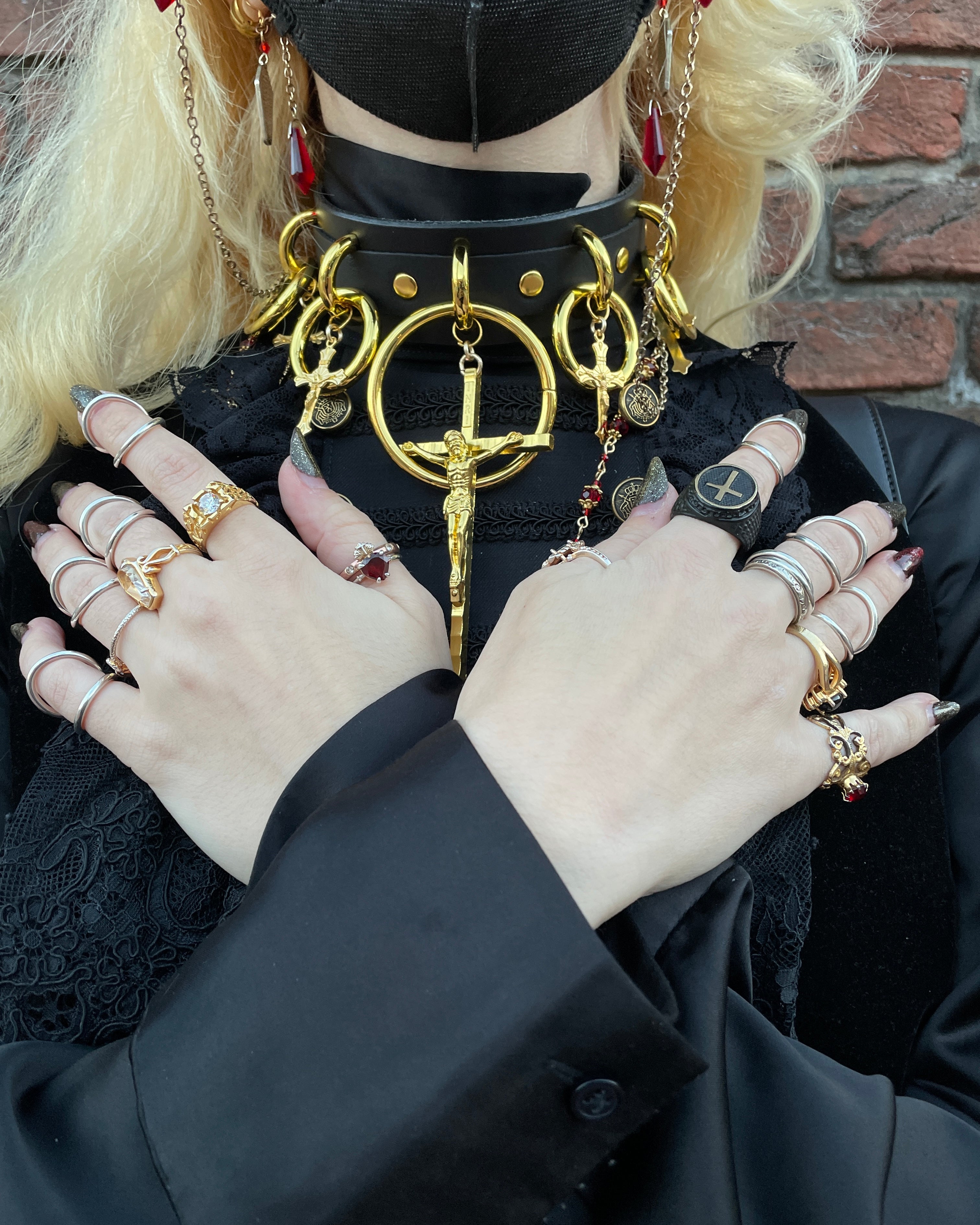 Person wearing black and golden cross choker with hands on chest