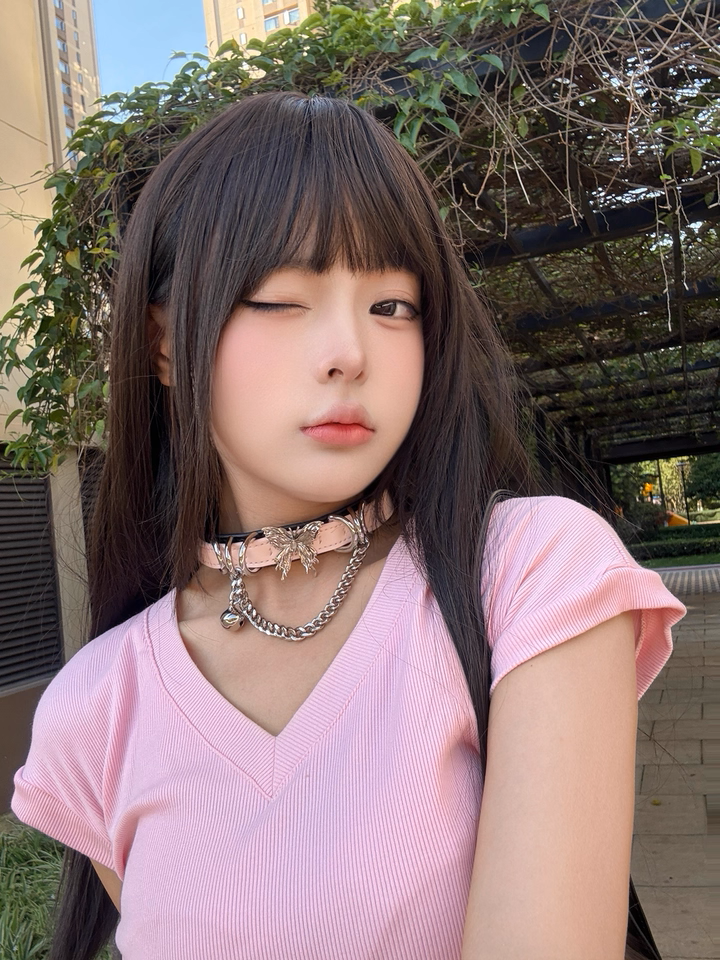 modelled photo of a black and pink butterfly bell collar, styled with long brown hair and pink t-shirt for a casual cute look.