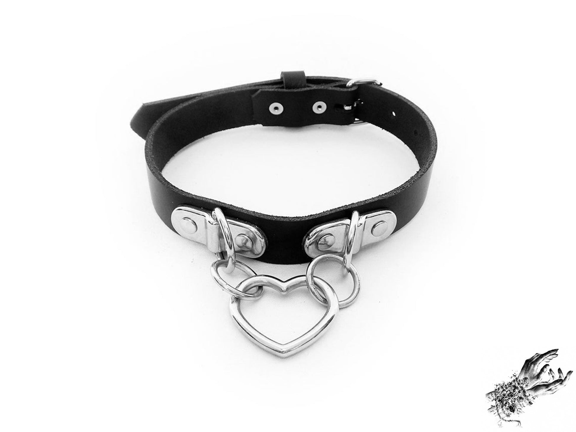 Handmade black leather collar featuring a central silver heart ring suspended by two D ring plates. Displayed on a white background.