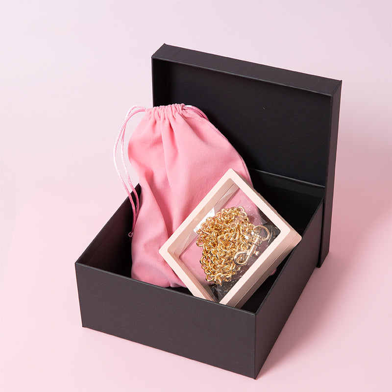 Packaging for choker and leash sets, showing a dust and scratchproof floating display box and pink velvet drawstring storage bag. Displayed on a pink background.