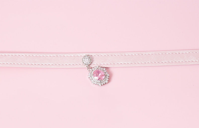 close-up of a pink leather collar showing the silver and pink crystal cameo pendant, displayed on a pink background.