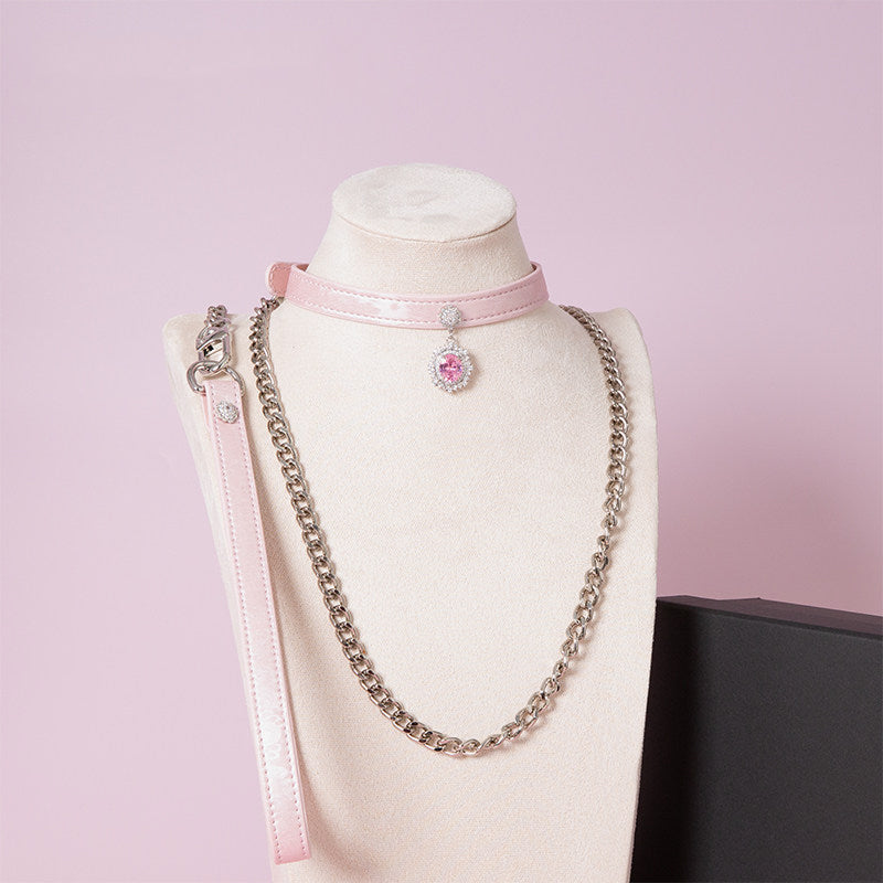 pink leather collar and leash set featuring a silver and pink crystal cameo pendant, detachable chain leash and leather hand strap, displayed on a white mannequin against a pink background.