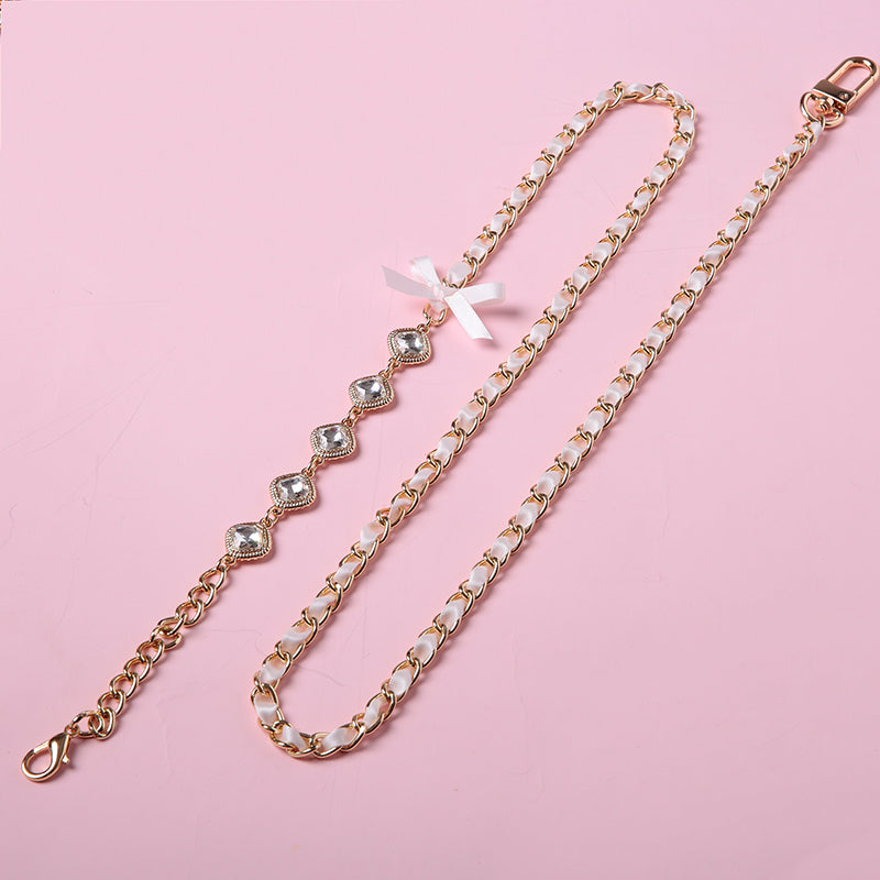 Detachable pink and gold crystal and chain leash featuring gold and clear crystal charms, pink ribbon bow applique, gold tone chain threaded with pink satin ribbon and swivel lobster clasps. Displayed on a pink background.