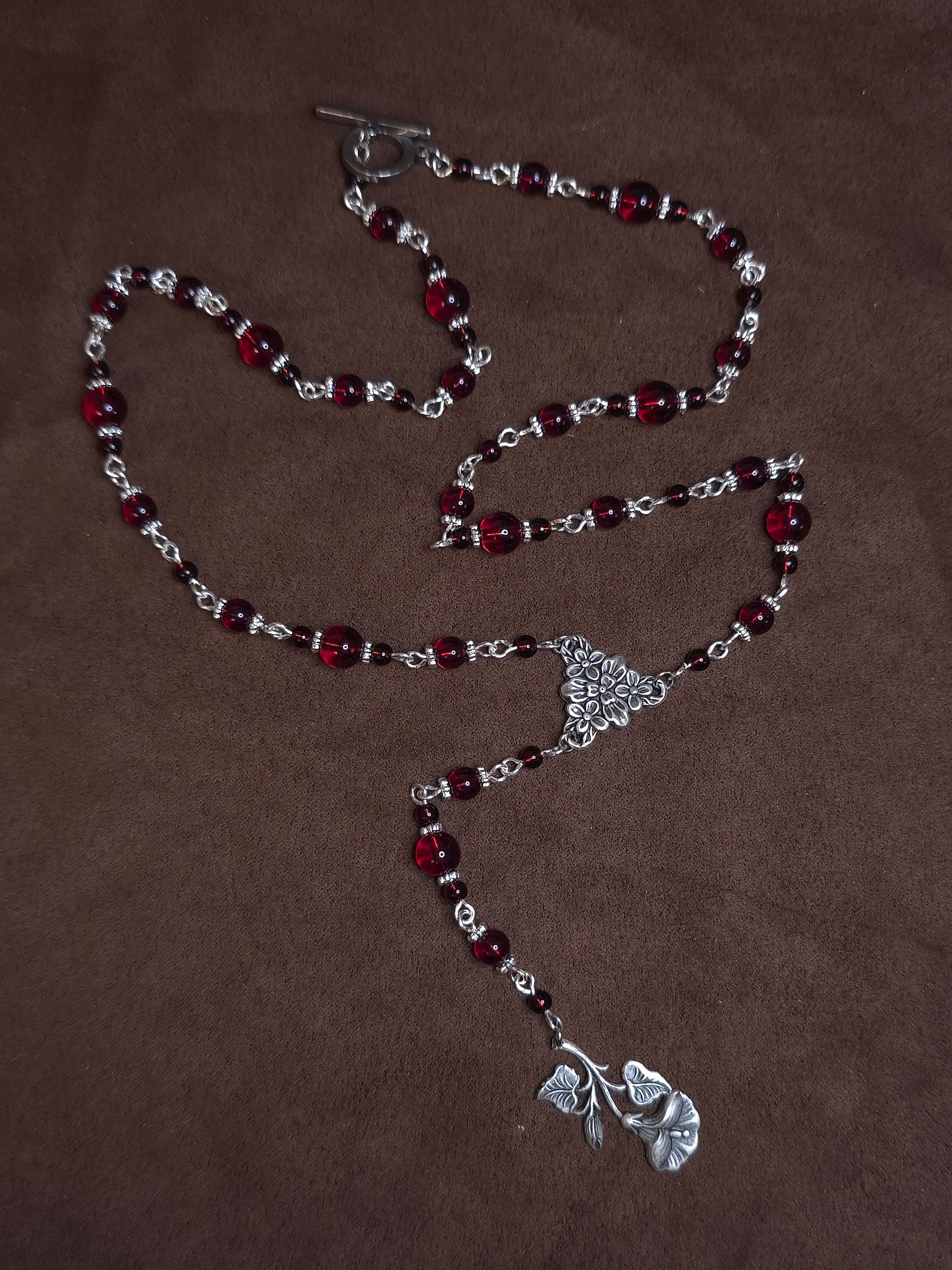 Necklace with red beads and silver clasp on a brown background