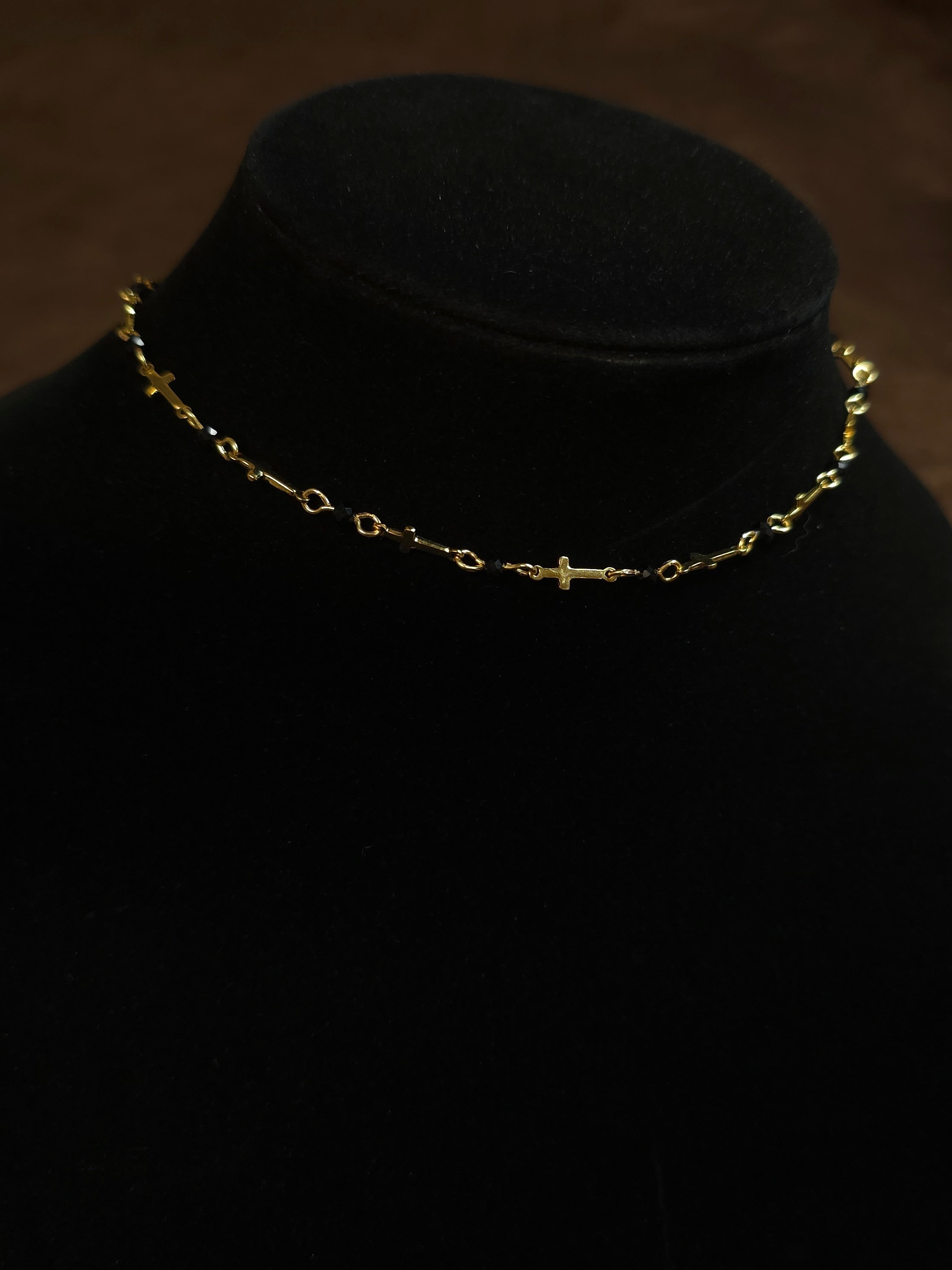 Gold necklace on a black mannequin head against a dark background