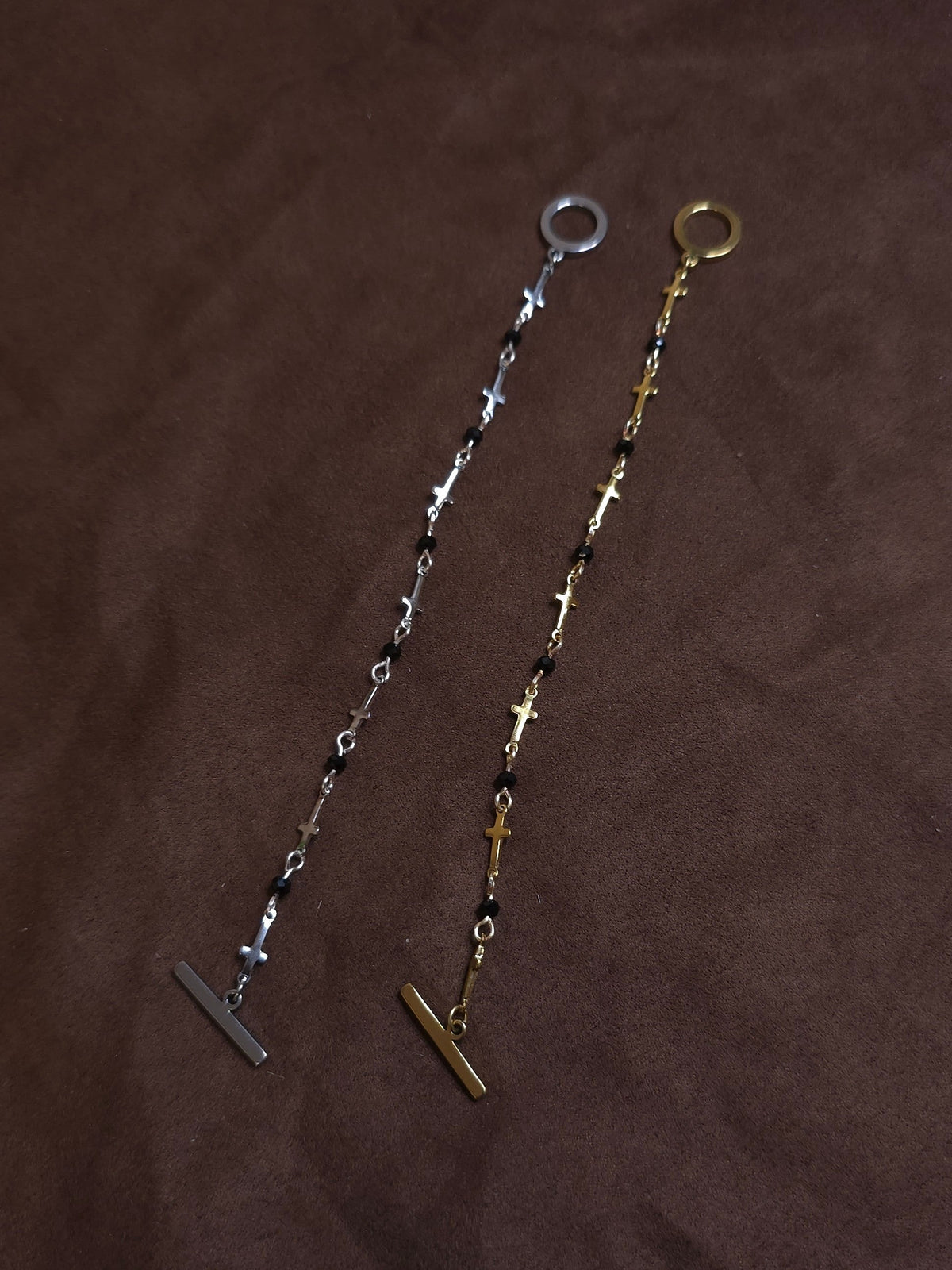 Two bracelets, one silver and one gold, on a brown fabric background