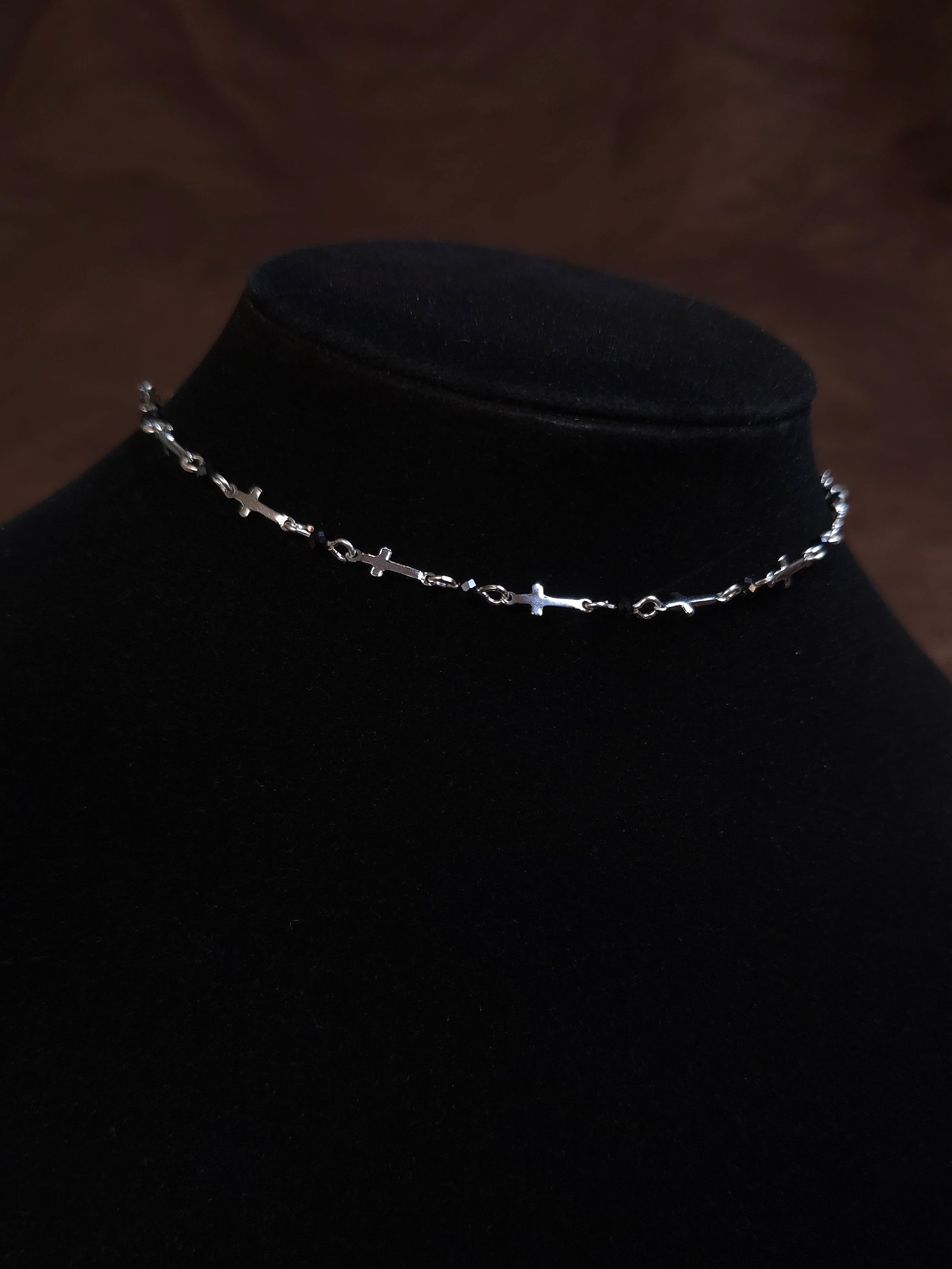 Silver chain necklace on a black mannequin bust against a dark background