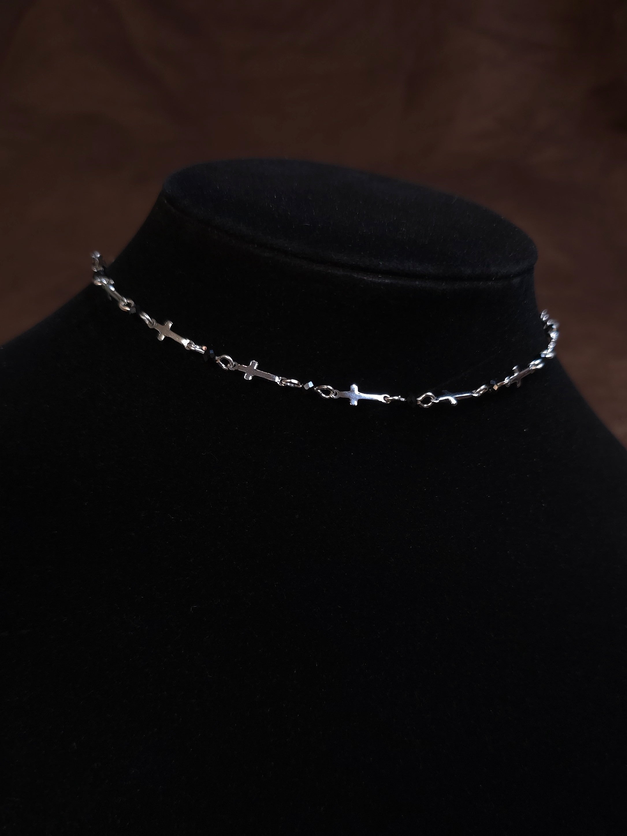 Silver chain necklace on a black mannequin bust against a dark background