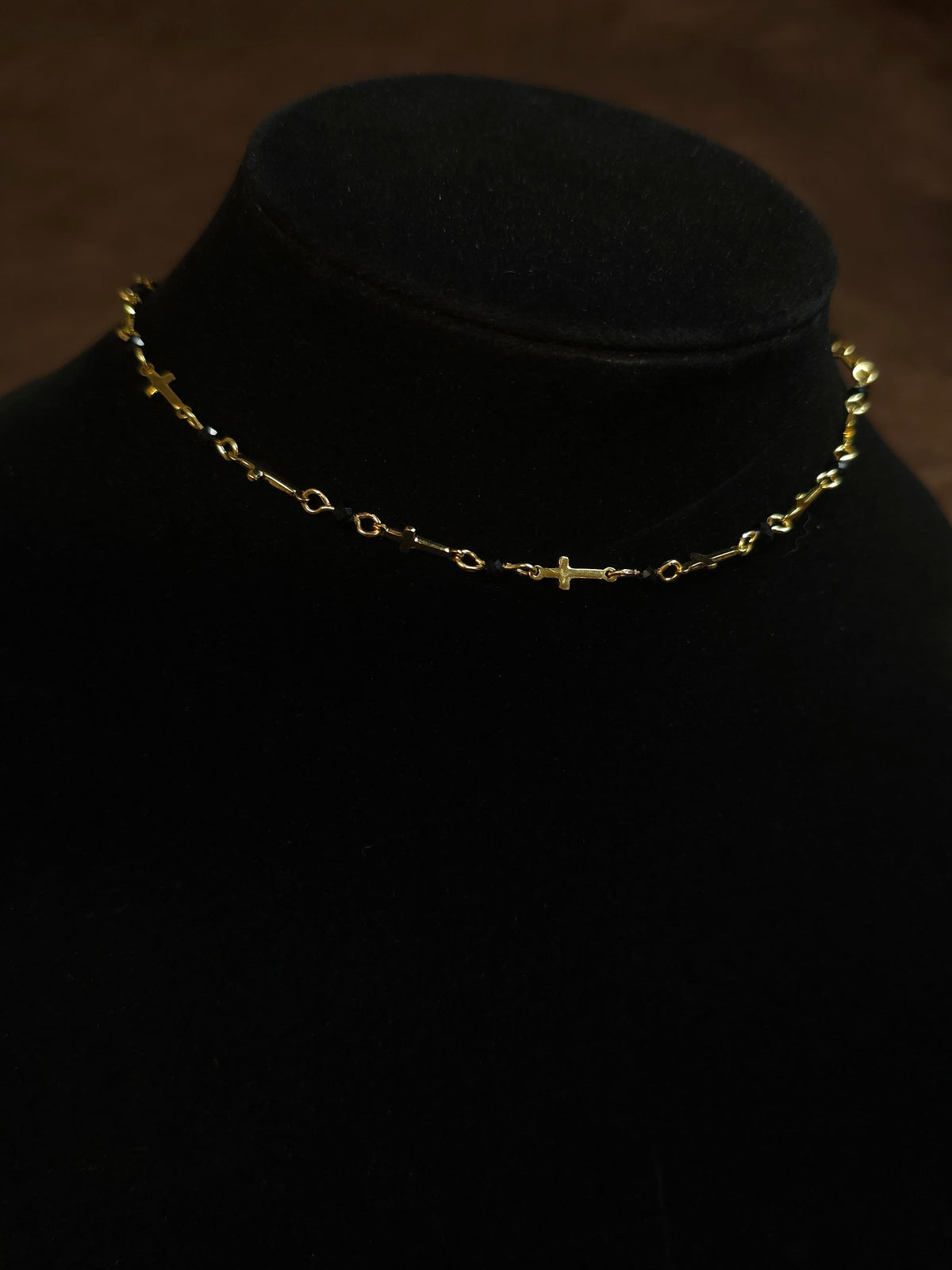 Gold necklace on a black mannequin head against a dark background