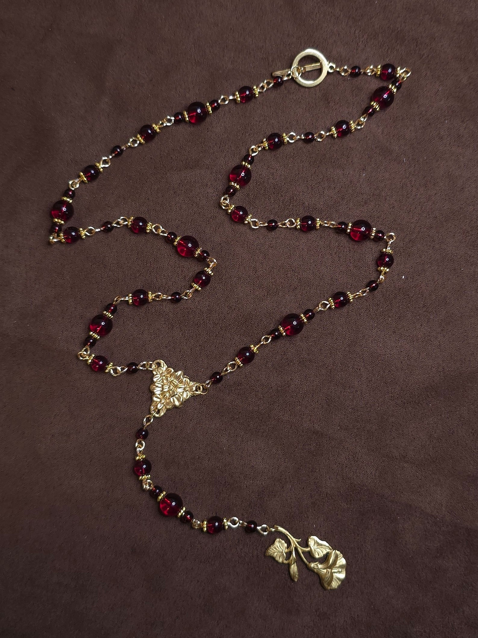 Red beaded golden rosary on brown background
