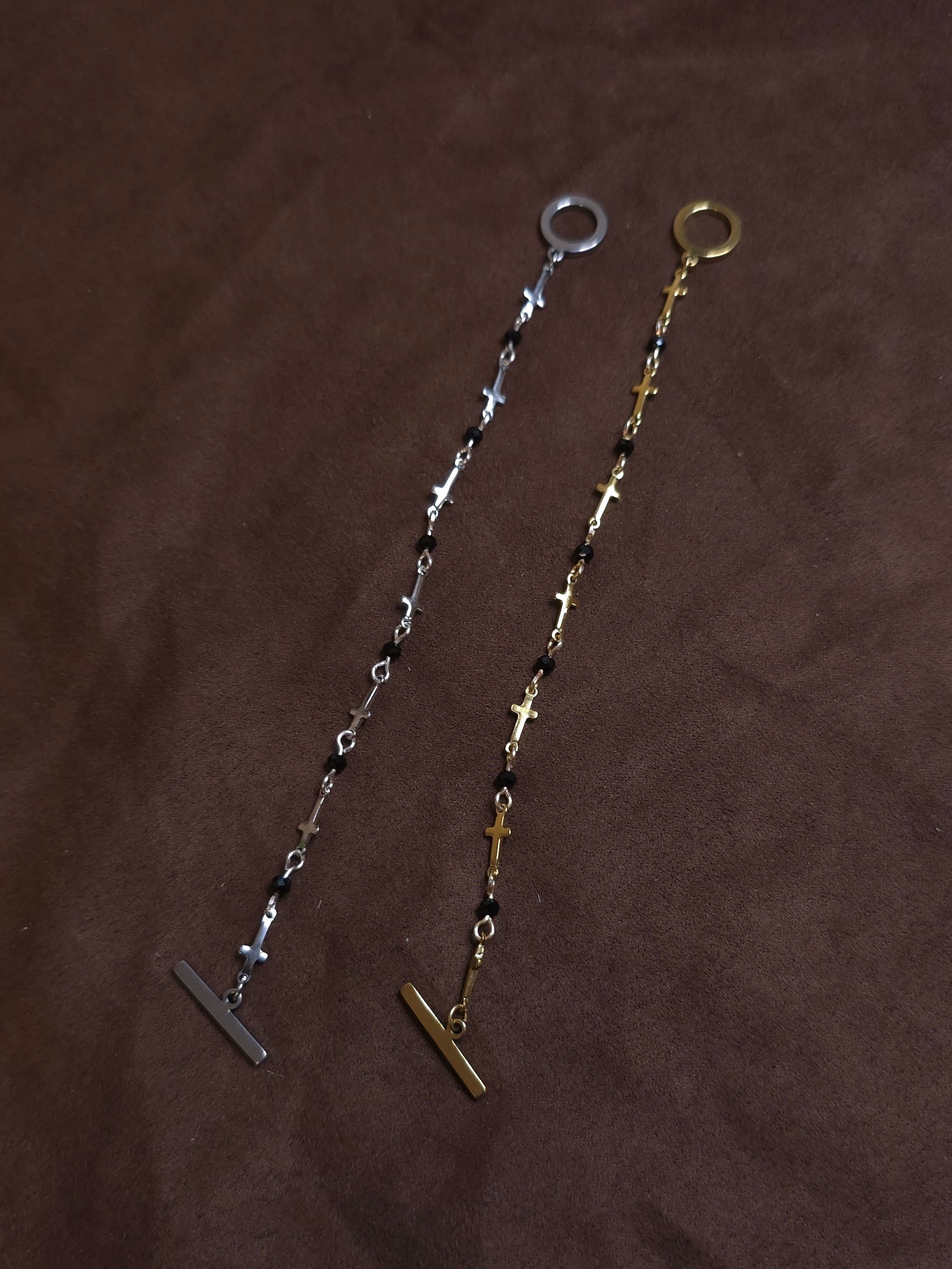 Two bracelets, one silver and one gold, on a brown fabric background