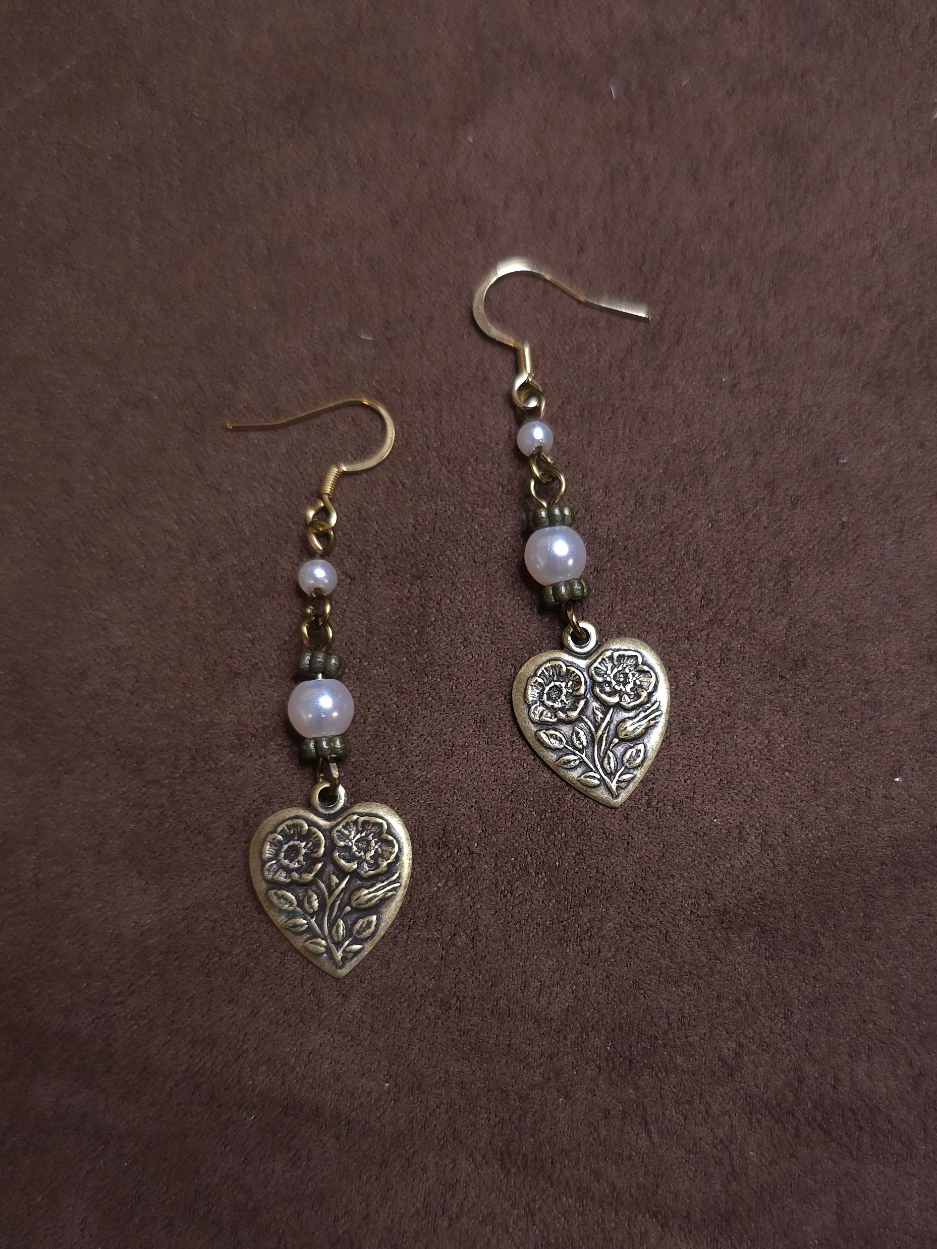 Heart-shaped earrings with floral designs on a brown background