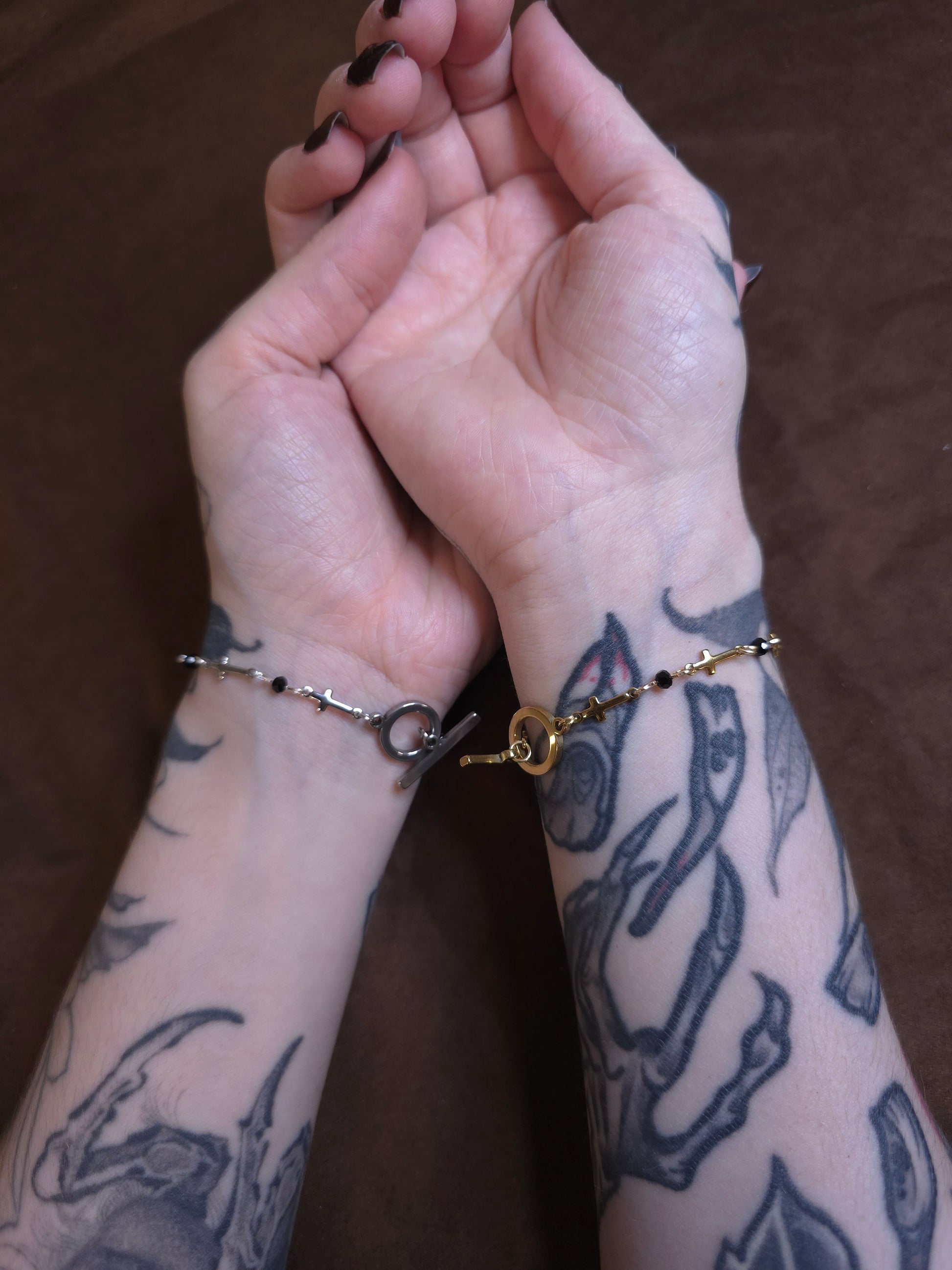 Two hands with tattoos holding each other against a brown background